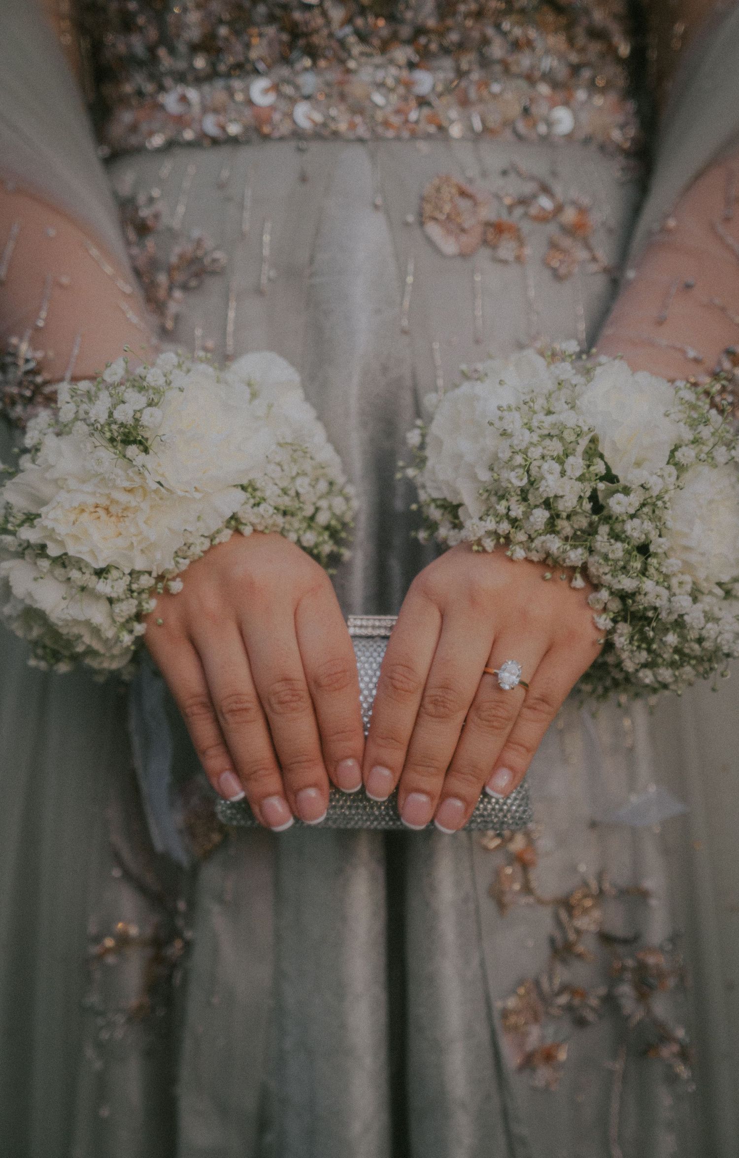 Close-up of hands holding delicate baby's breath bouquets against sage green dresses.