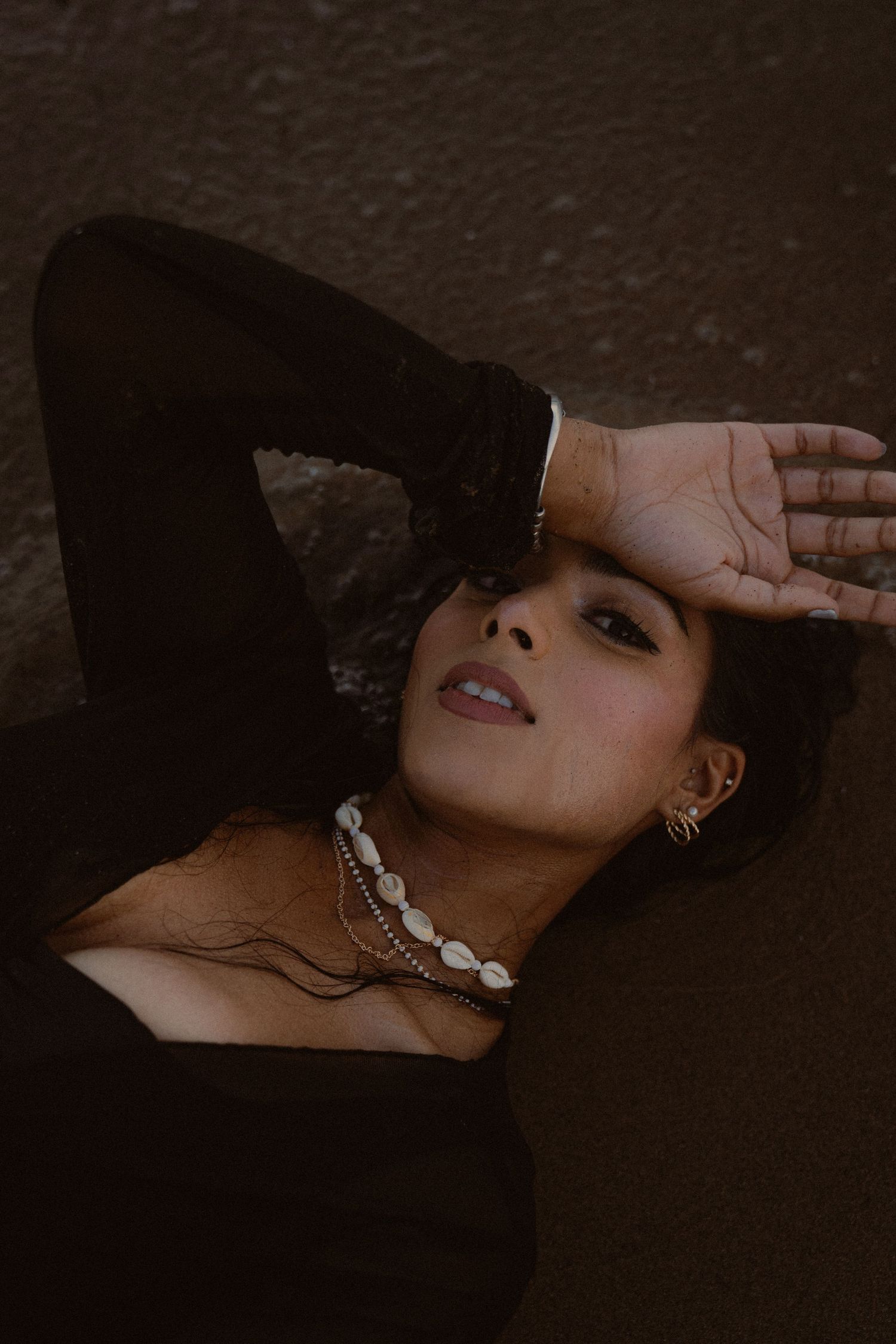 Dramatic close-up portrait series with hands and jewelry in dark lighting.