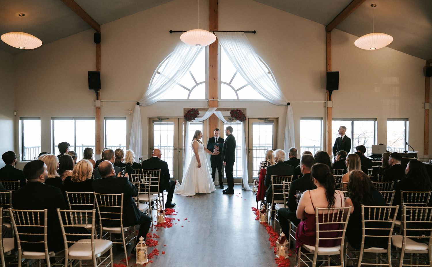Wedding ceremony venue with white chairs and vaulted ceiling windows.