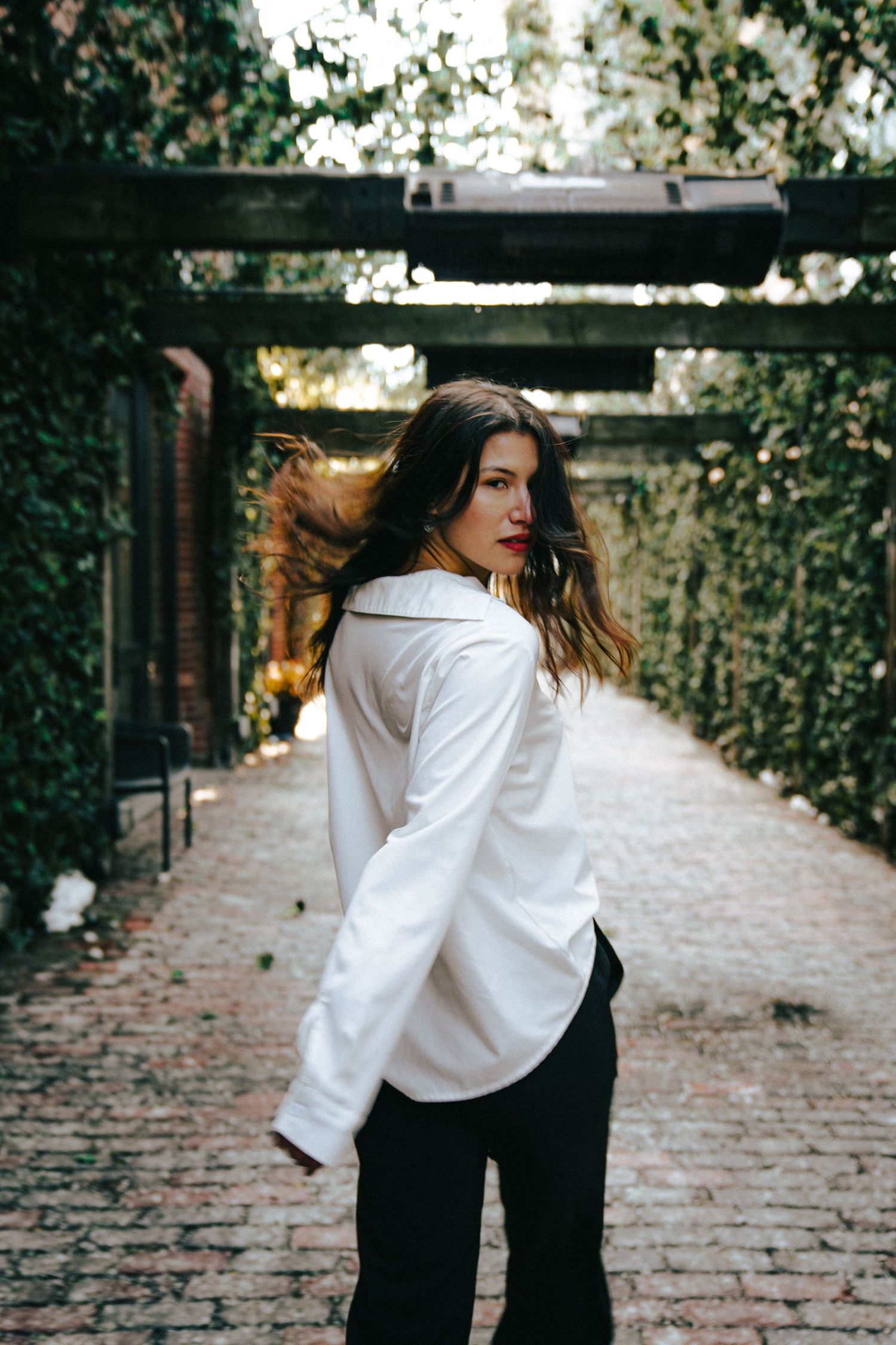 Person in white shirt and dark pants moving dynamically on cobblestone path.