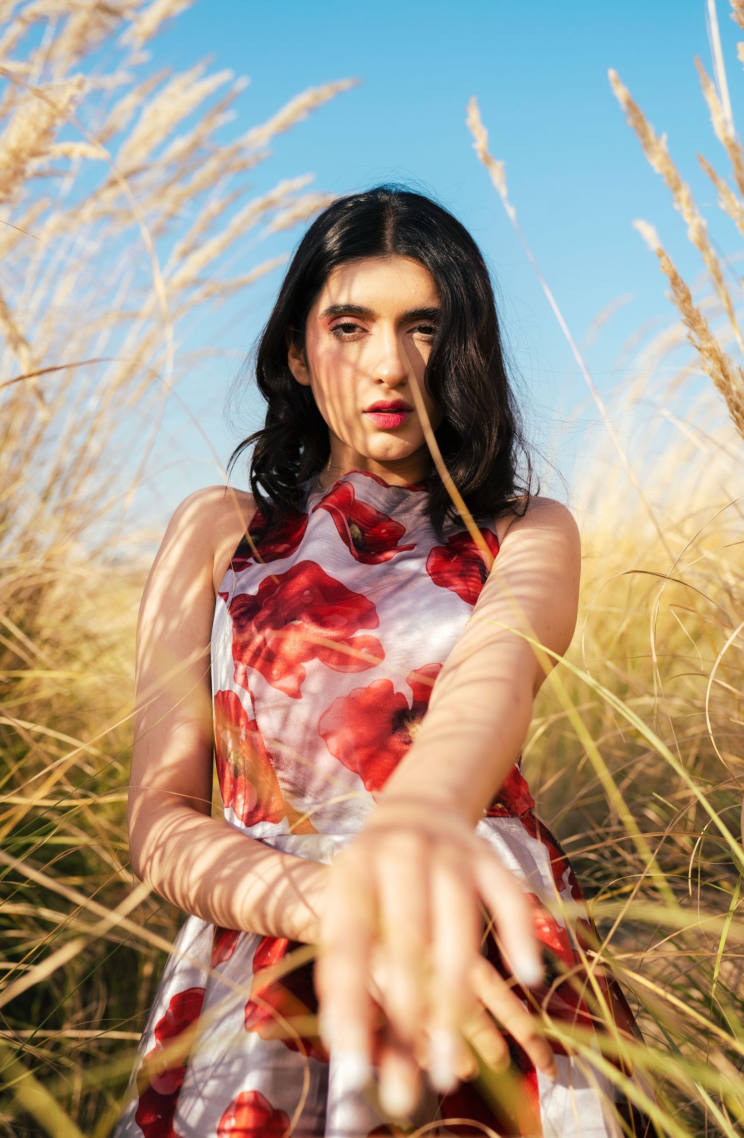 Artistic portrait in golden wheat field with flowing red and white dress.