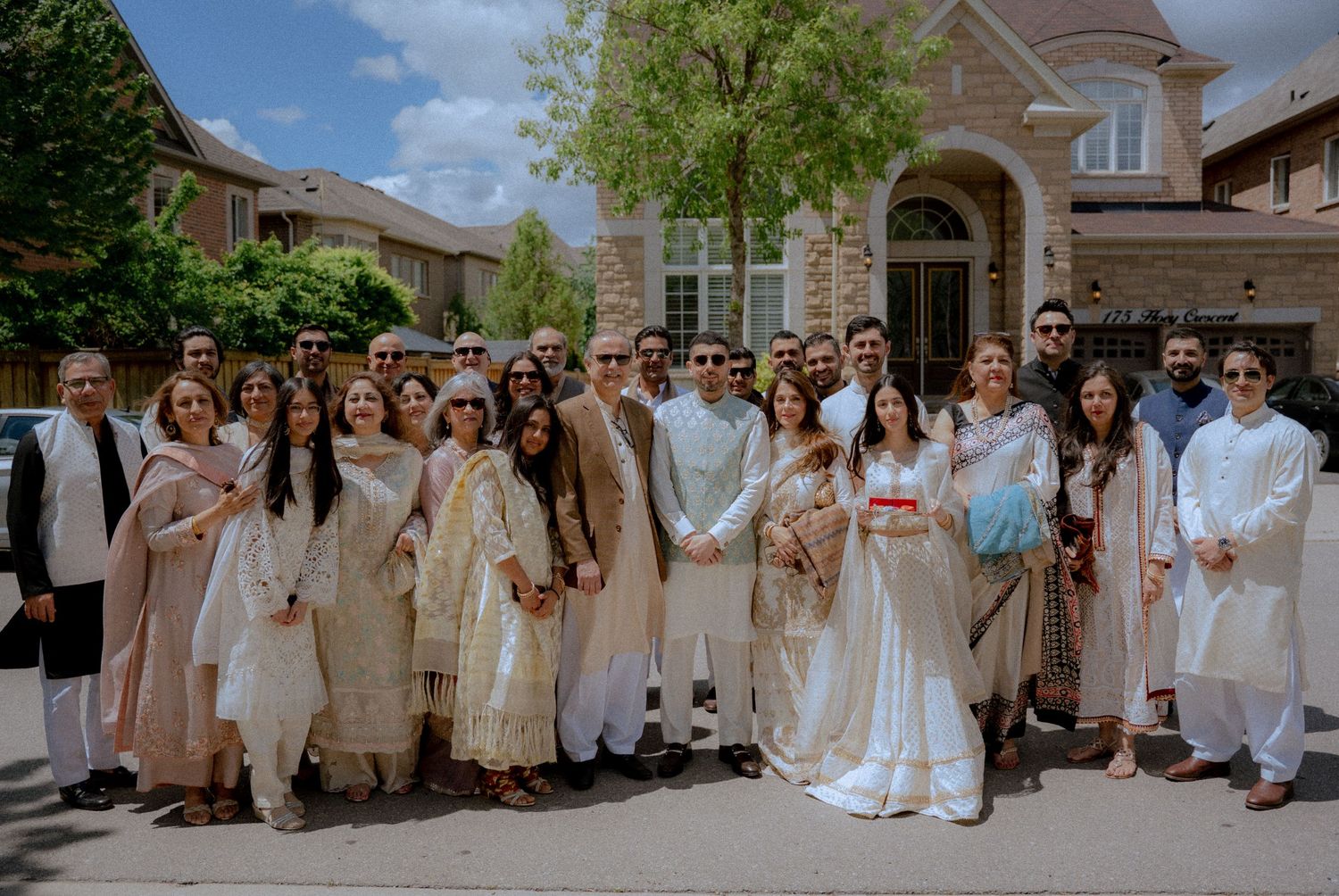Wedding party lineup wearing coordinated white and beige outfits outdoors.