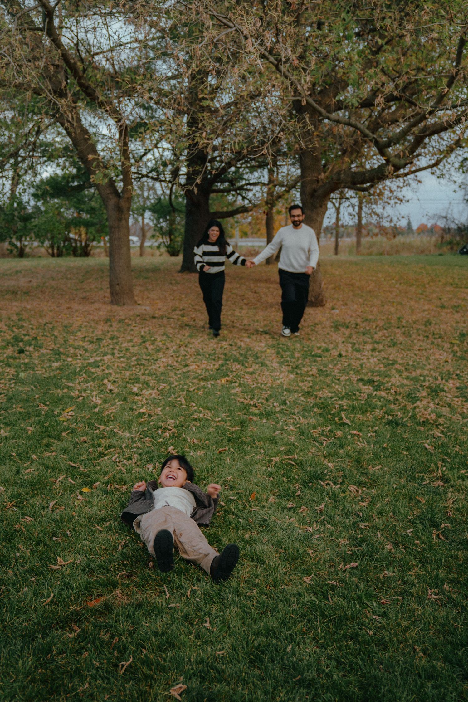 Playful autumn photo session in park with falling leaves.
