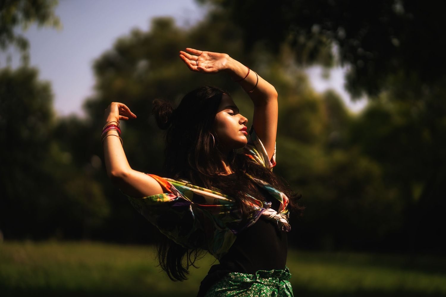 Graceful dance pose captured in golden sunlight among trees and natural surroundings.
