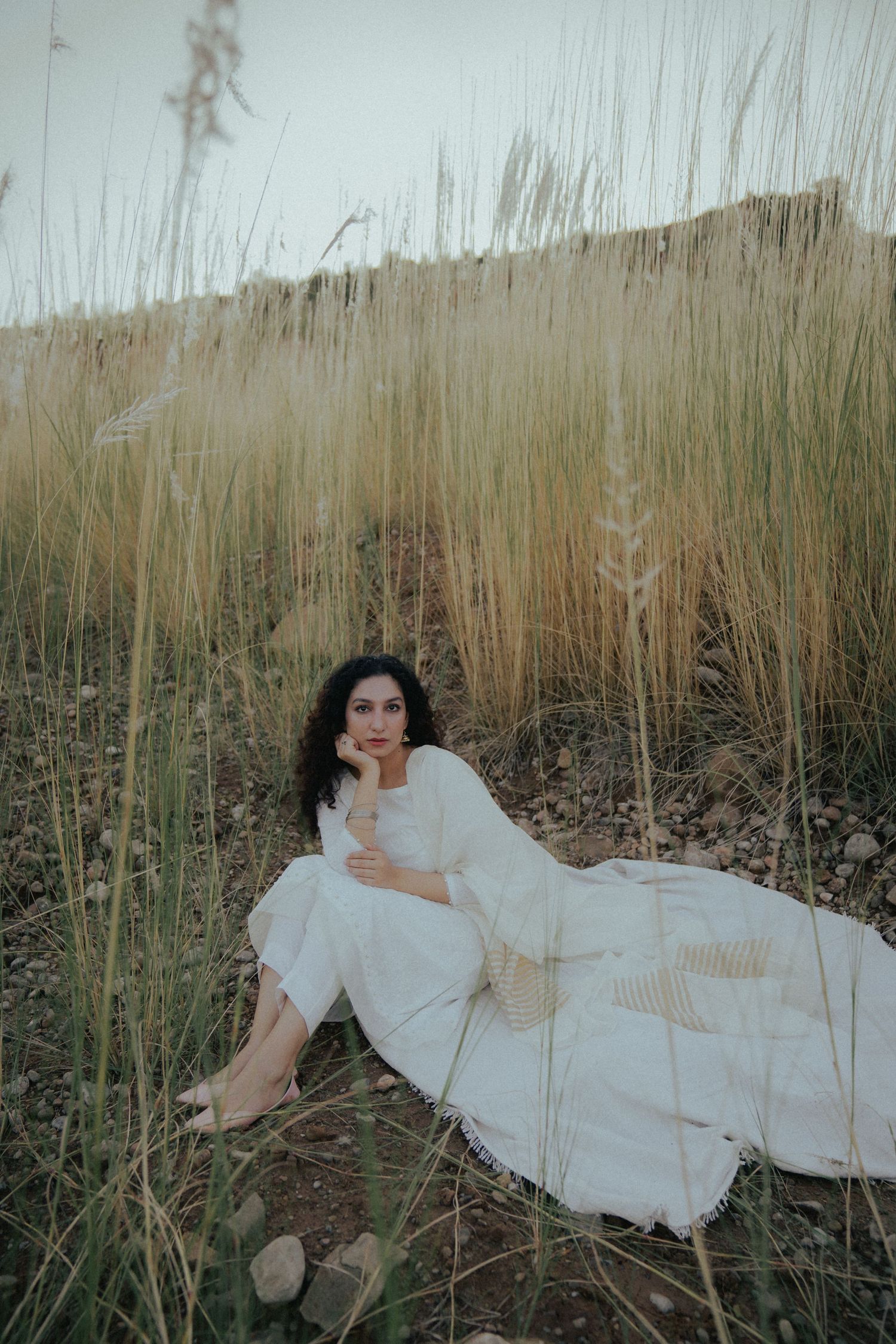 Ethereal portrait in tall grass with flowing white dress at golden hour.