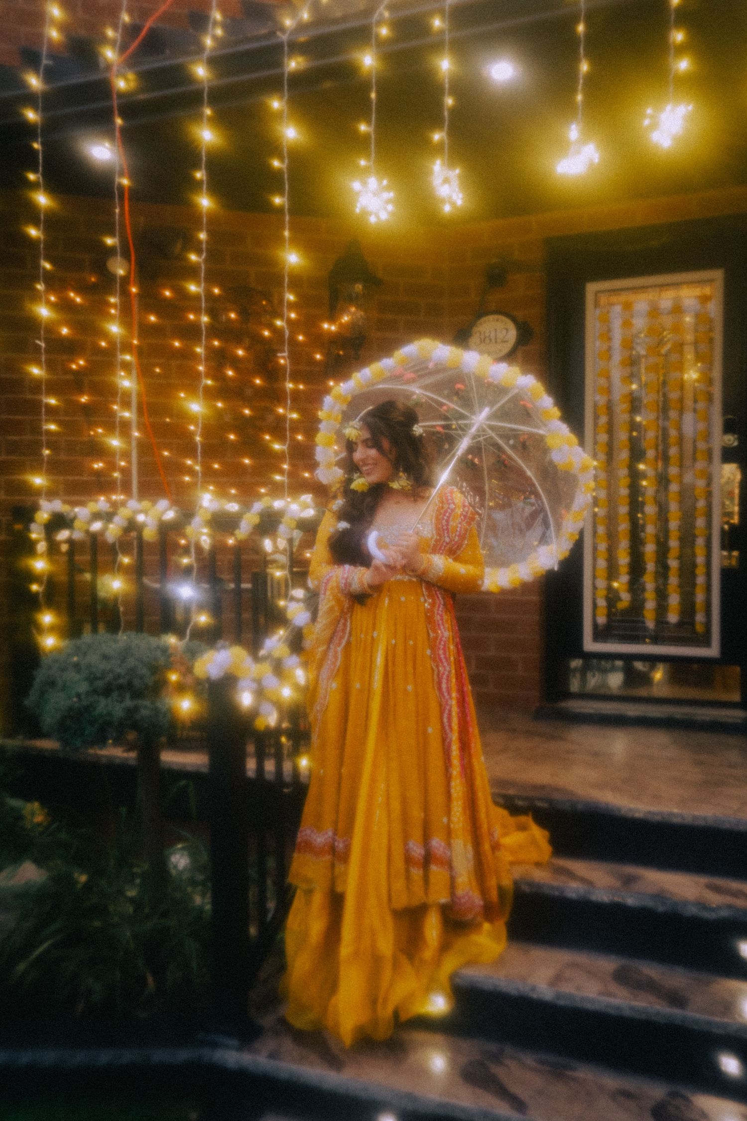 A person in a yellow dress twirls under hanging fairy lights at night creating a magical ambiance.
