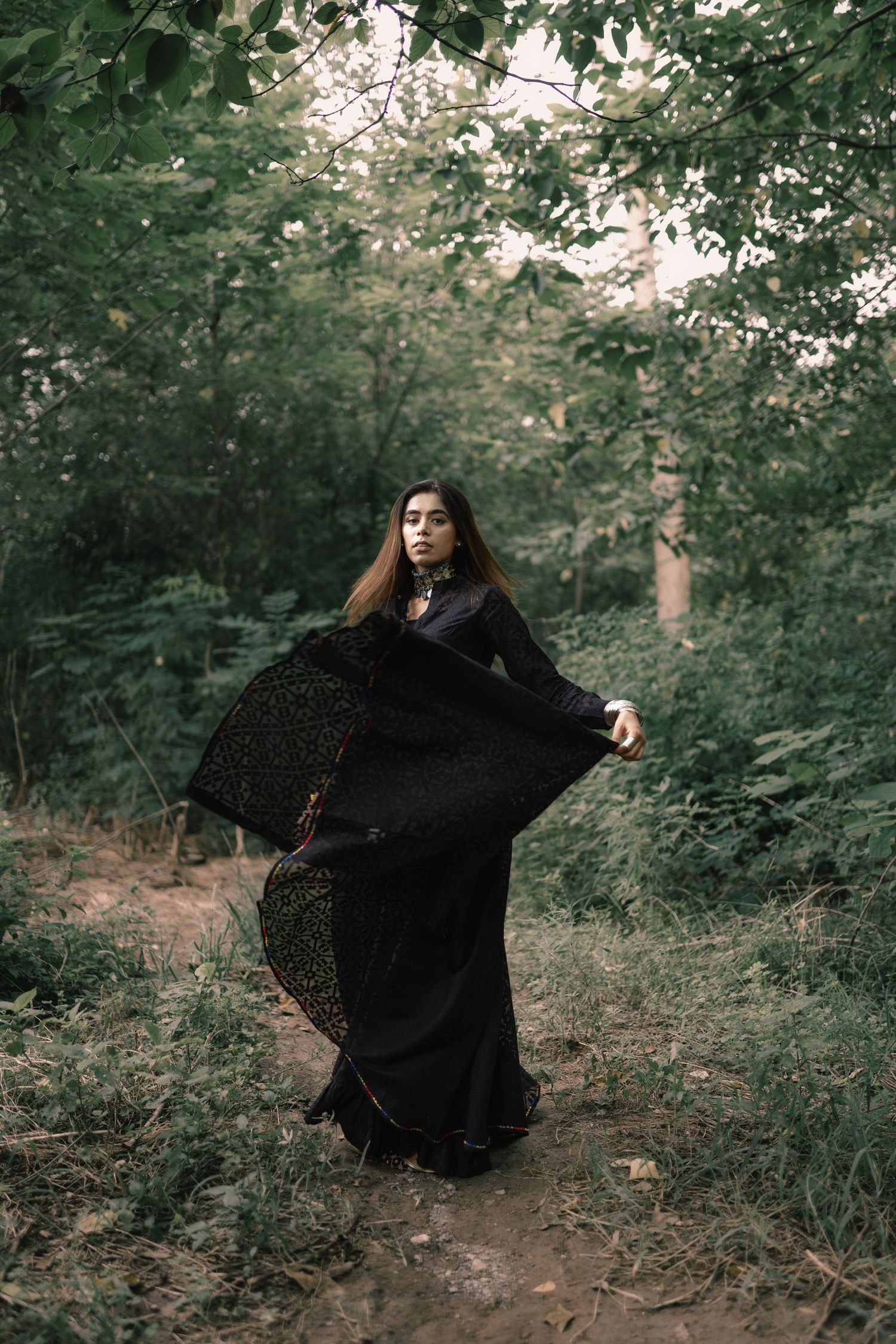Dramatic sequence of flowing black dress movement in forest setting.