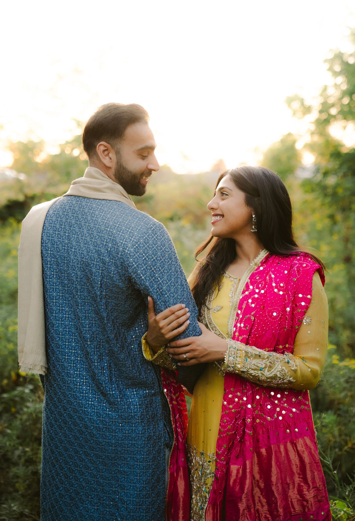 A couple shares joyful moments in a garden setting with the person in pink dress laughing.