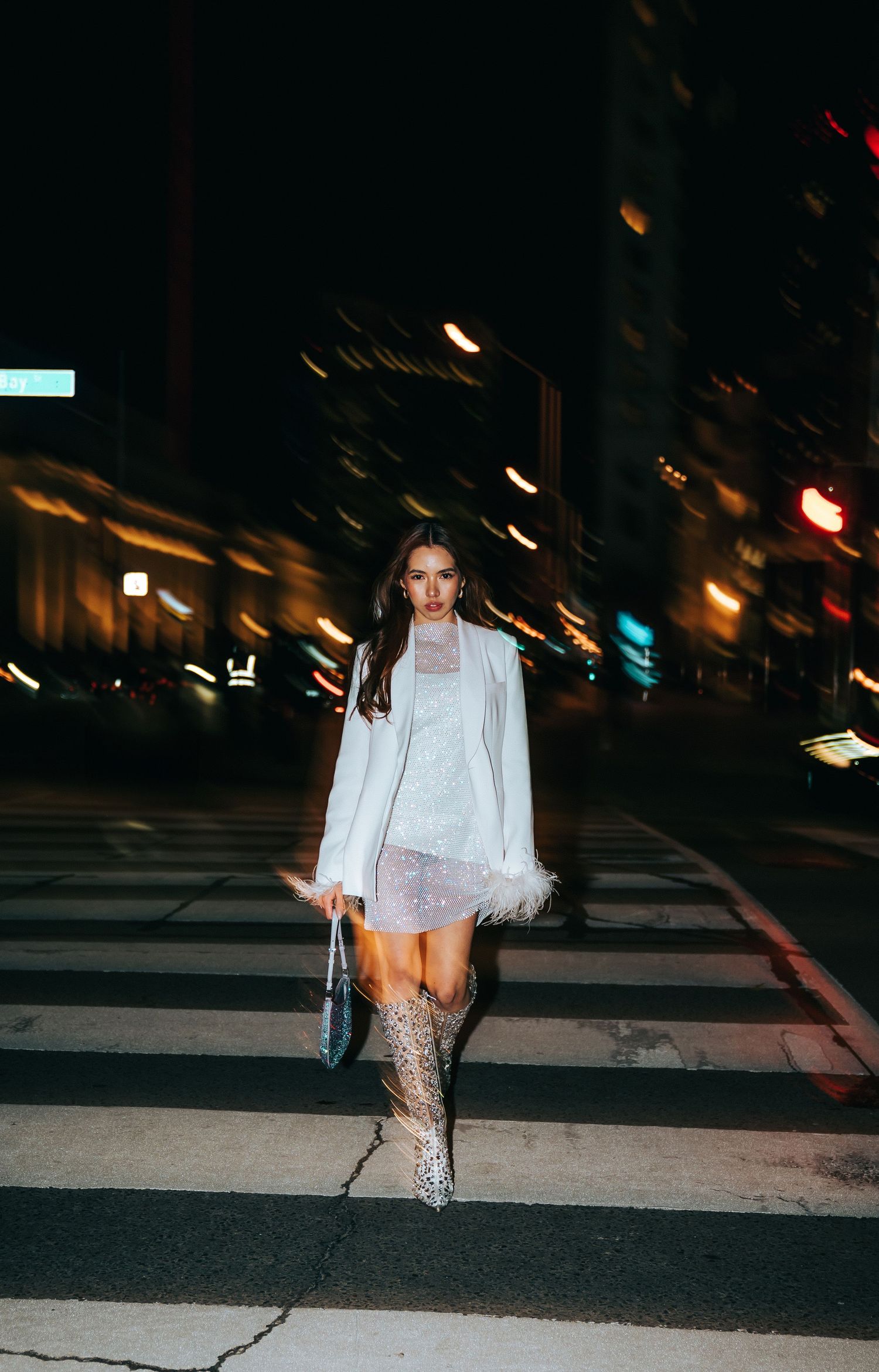 Fashion photo sequence of someone walking in white outfit and sparkly boots on city street at night.