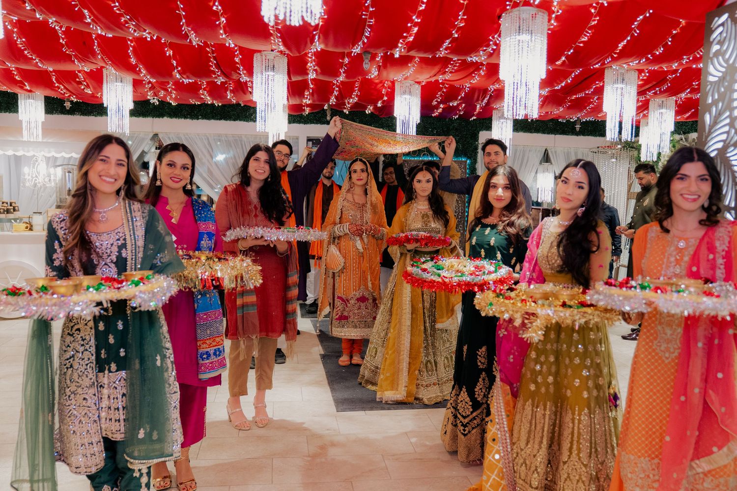 Festive celebration with colorful traditional outfits and red ceiling decorations.