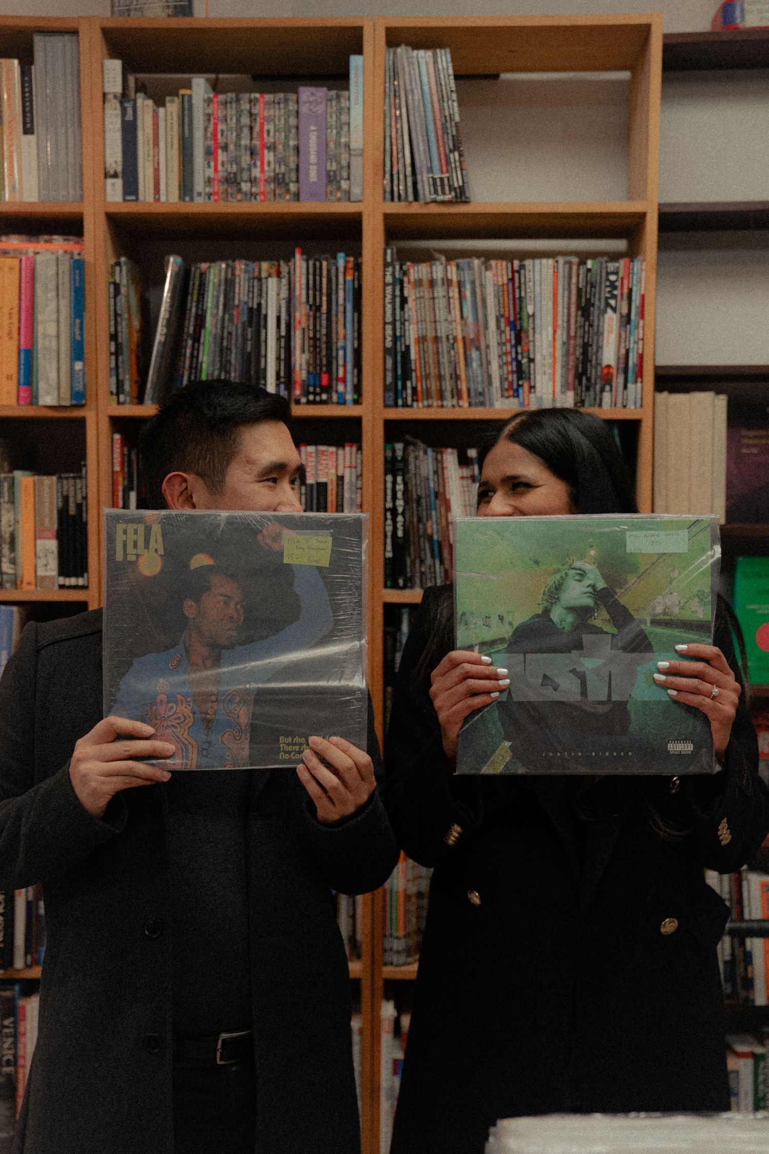 People holding vinyl records in front of library bookshelves.