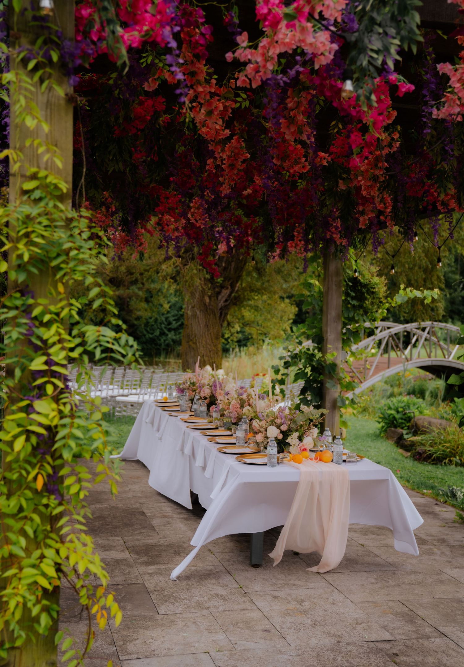 Elegant outdoor wedding reception tables set under blooming pink floral trees.