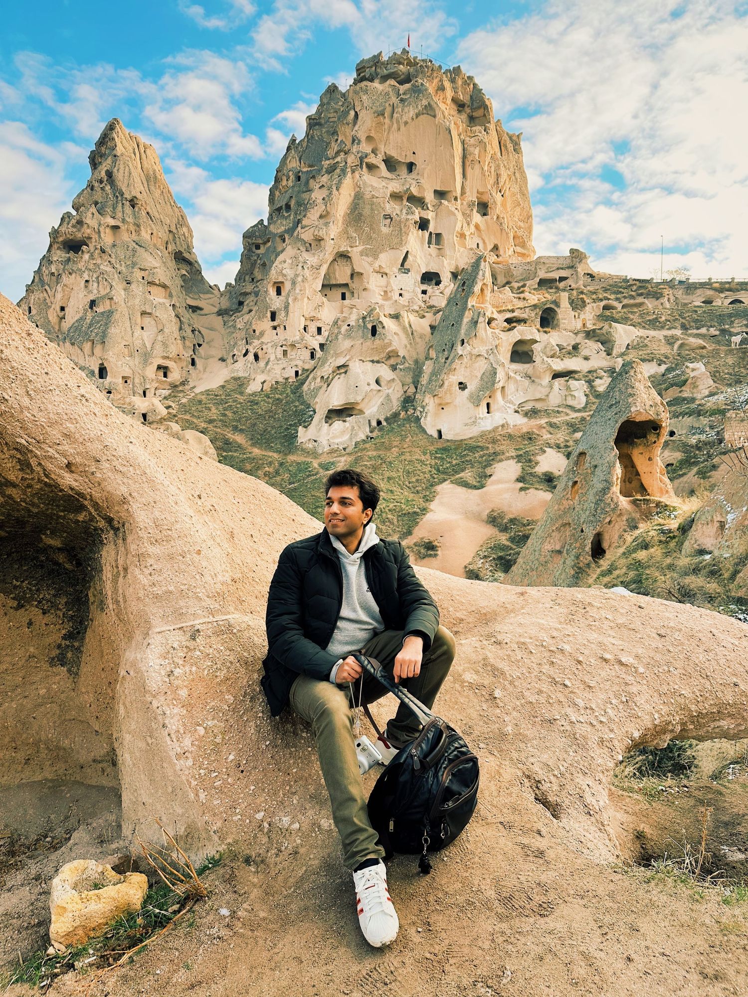 Rocky landscape in Cappadocia with carved stone formations against blue sky.