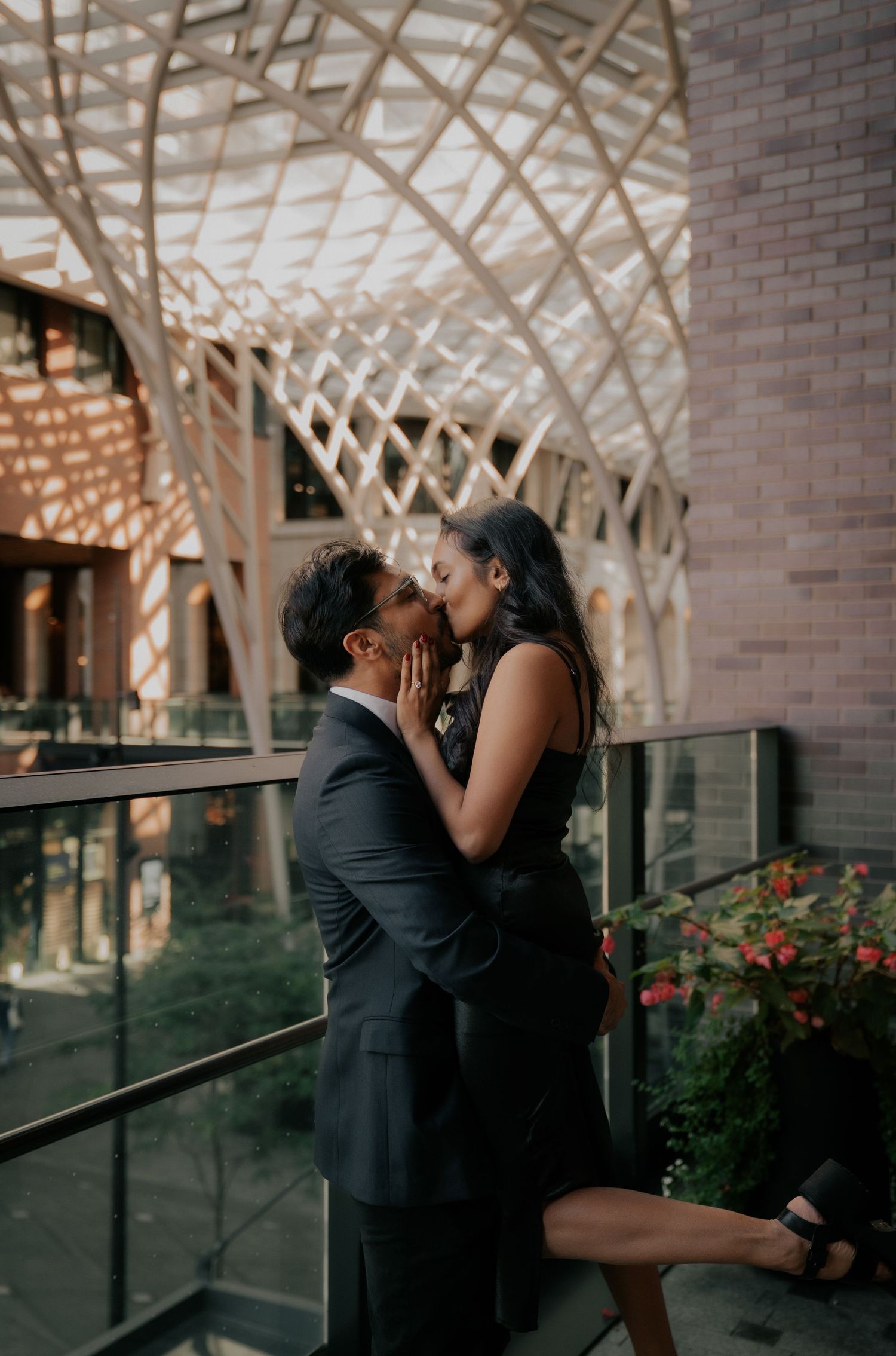 A romantic moment shared under a modern architectural structure with wooden beams.