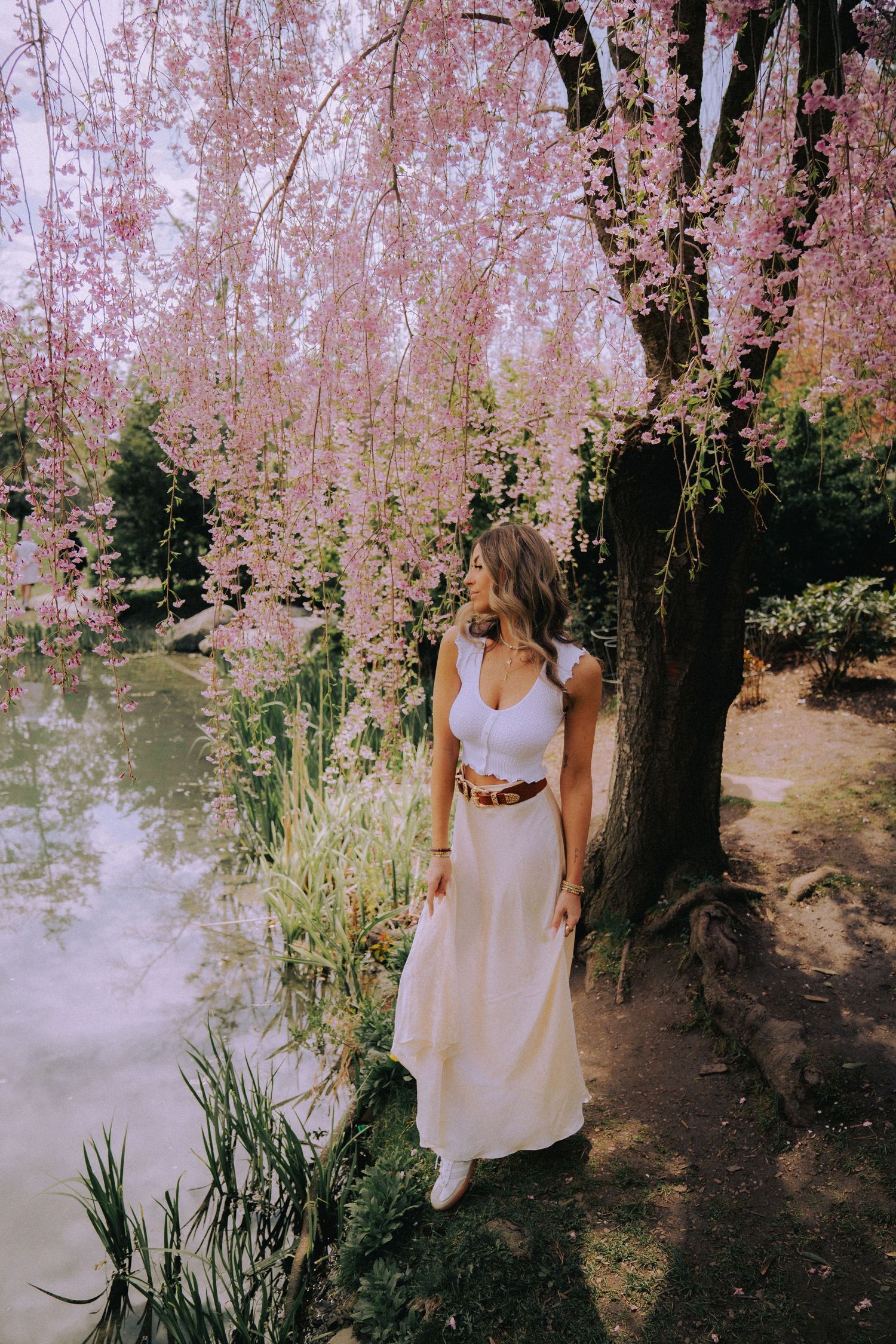 Ethereal spring portrait in white dress among blooming cherry trees.
