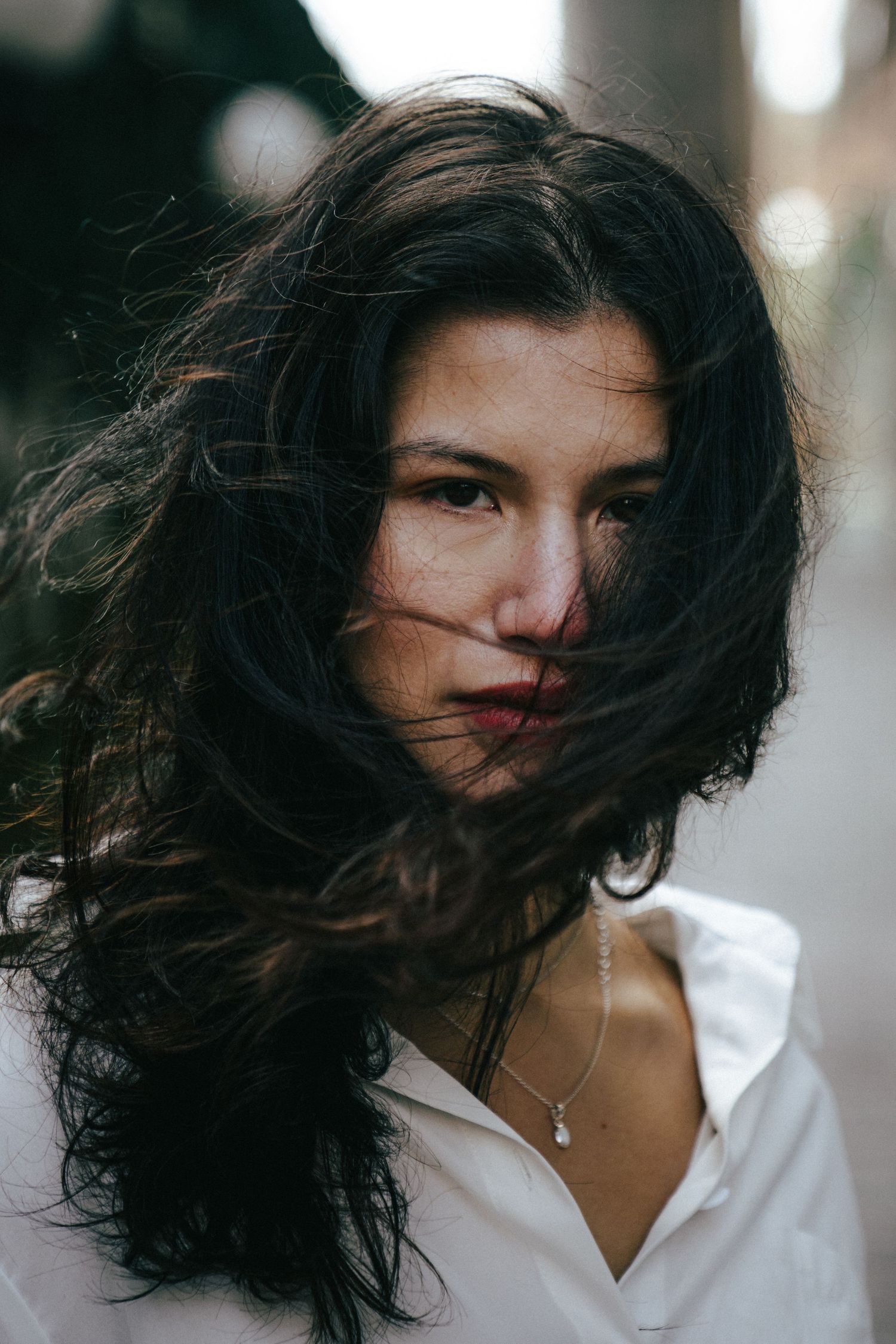 A dramatic portrait series showing windswept dark hair against a blurred background.