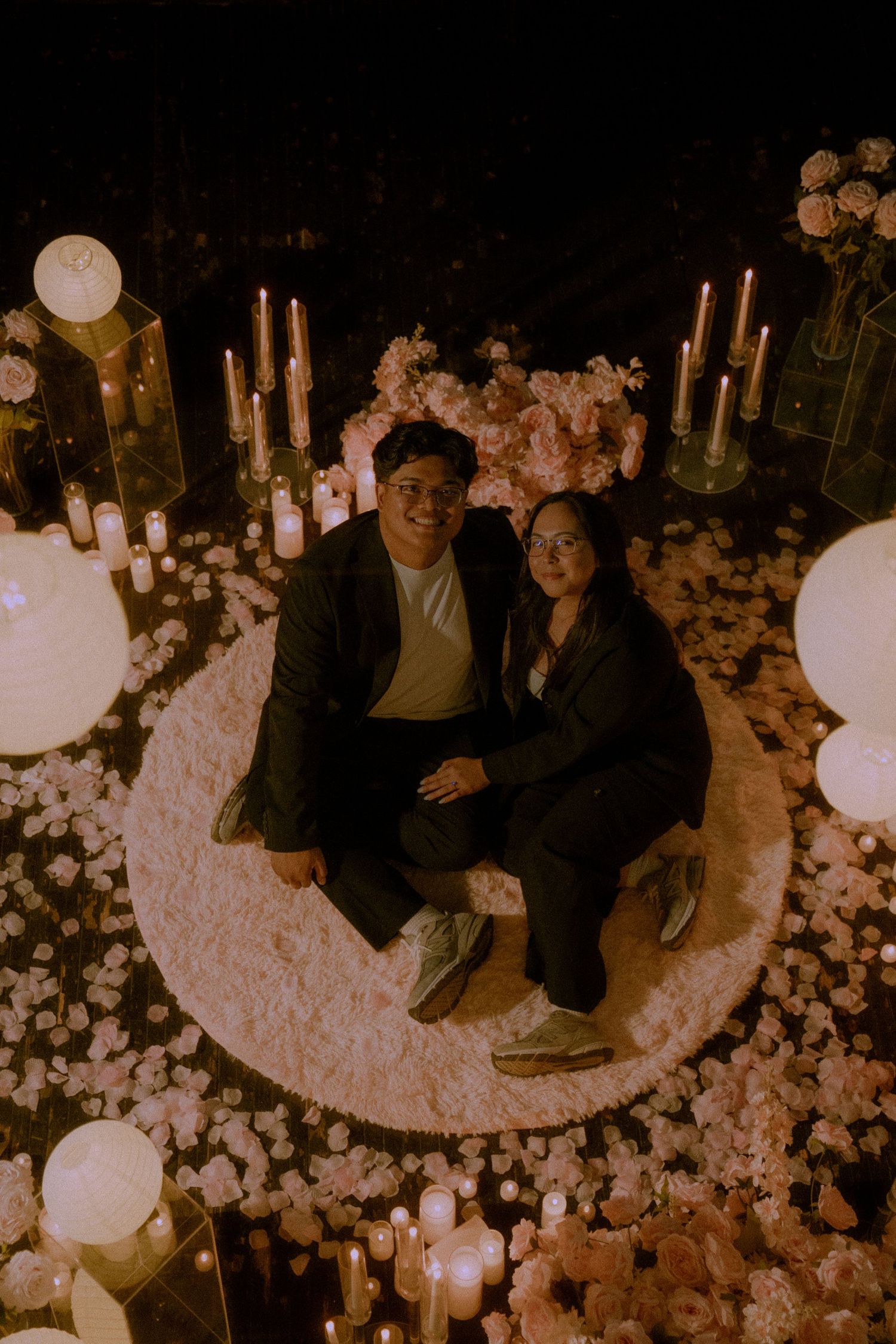 A romantic evening setup with glowing paper lanterns and flower petals creating an intimate atmosphere.