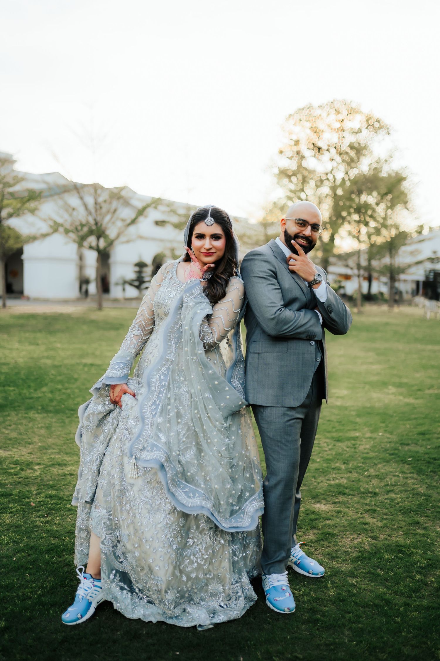 Playful wedding couple posing on grass with mountains in background.