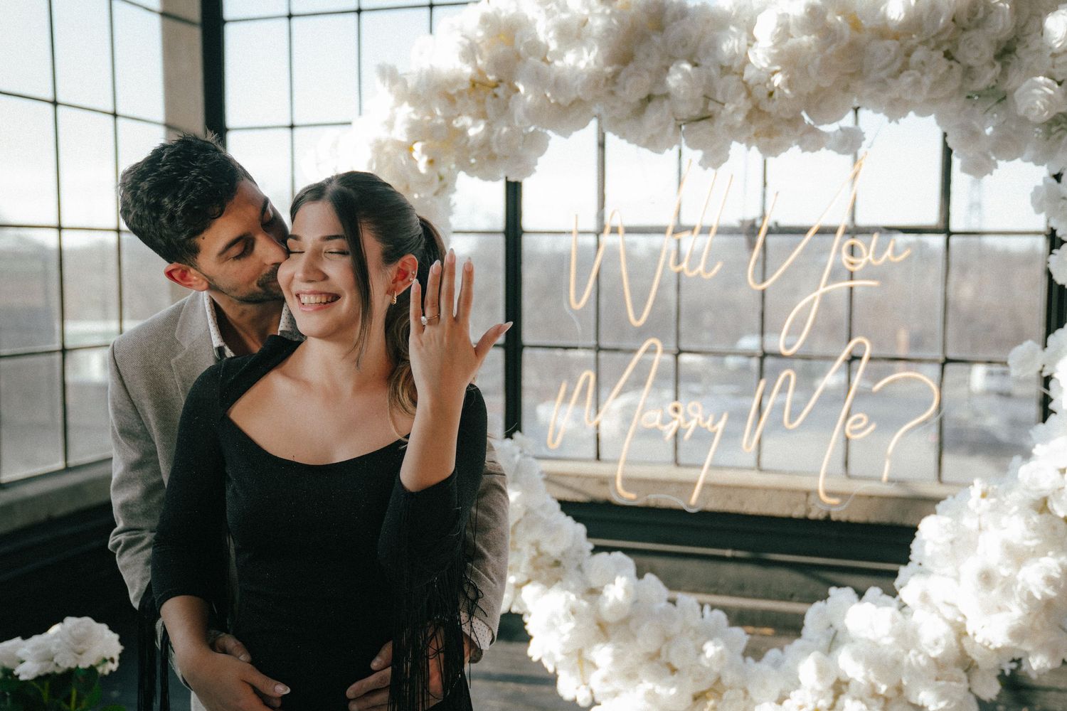 A romantic moment captured in an industrial space decorated with white balloon clouds and neon signs.