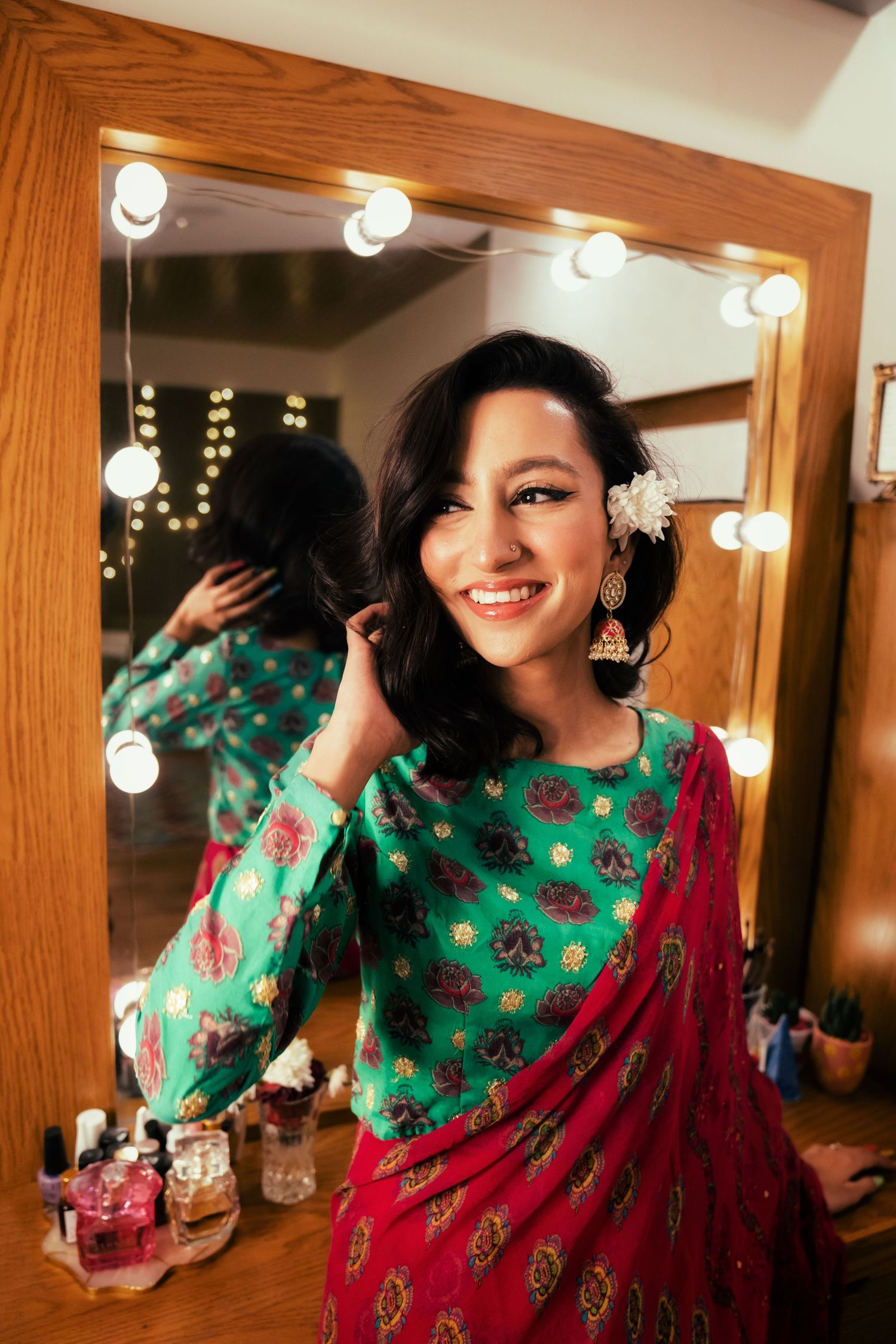 Series of mirror reflections showing a vibrant green and red traditional outfit with dressing room lighting.
