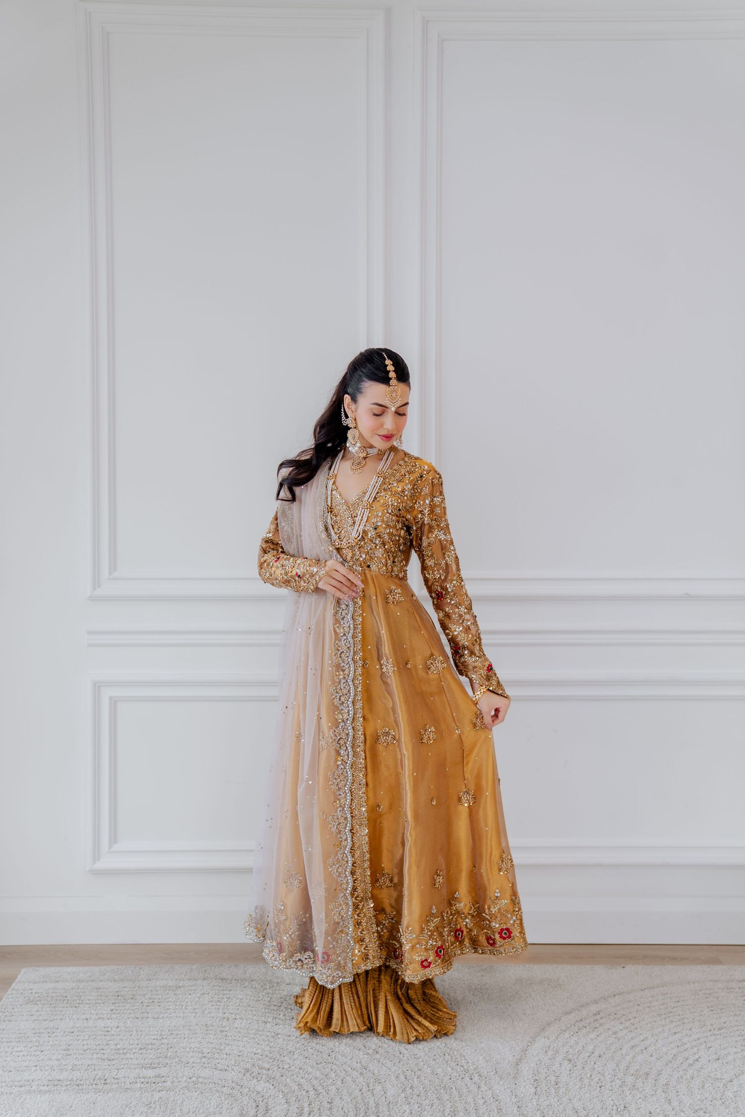 Traditional South Asian formal wear in rich gold with detailed embroidery against white backdrop.