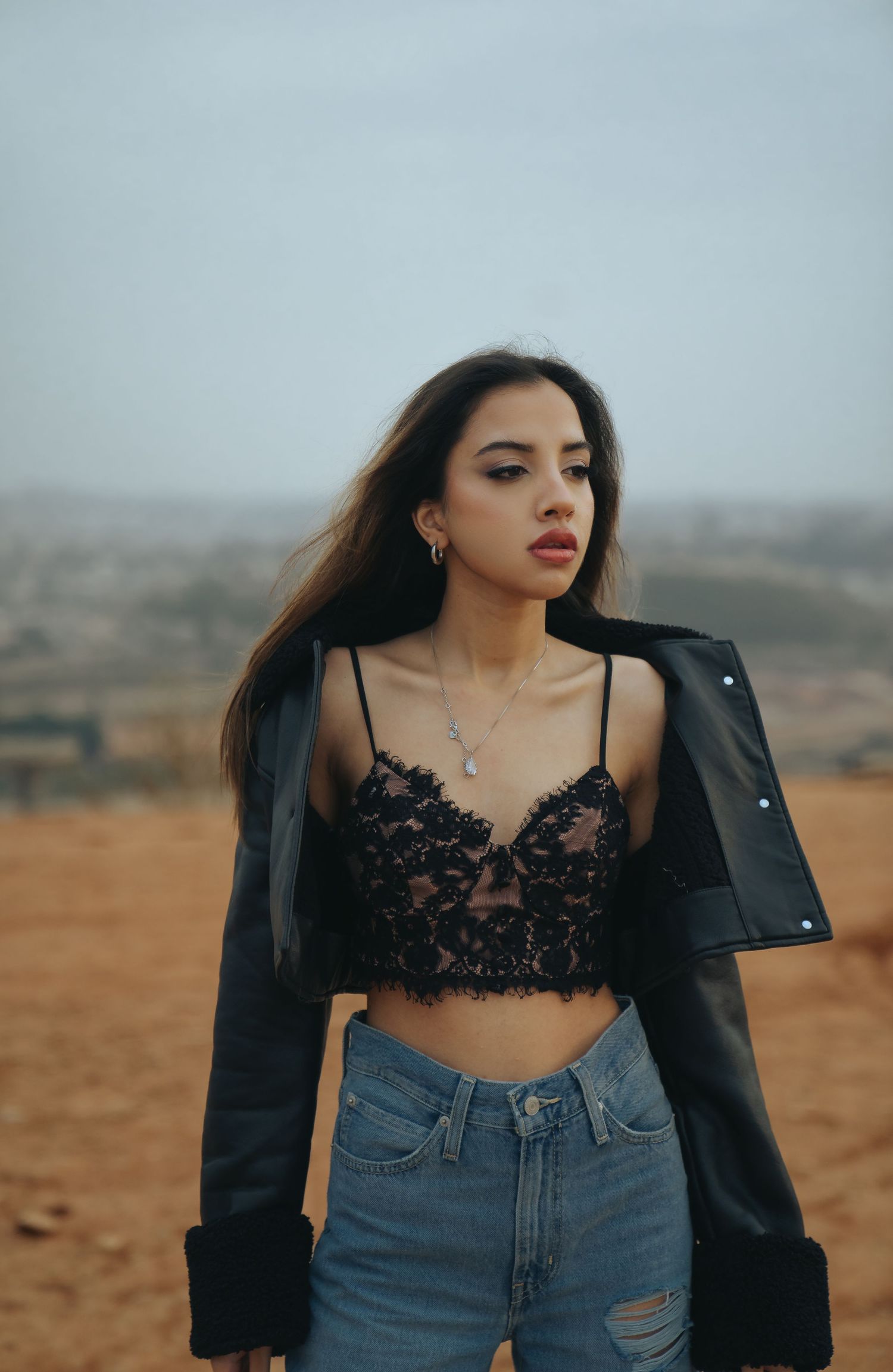 Fashion photography in desert setting with leather jacket and lace top combination.