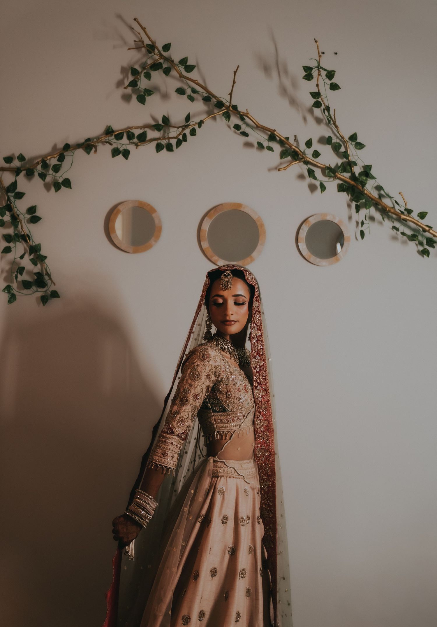 Traditional bridal attire with intricate embroidery photographed against wall with decorative mirrors and vines.