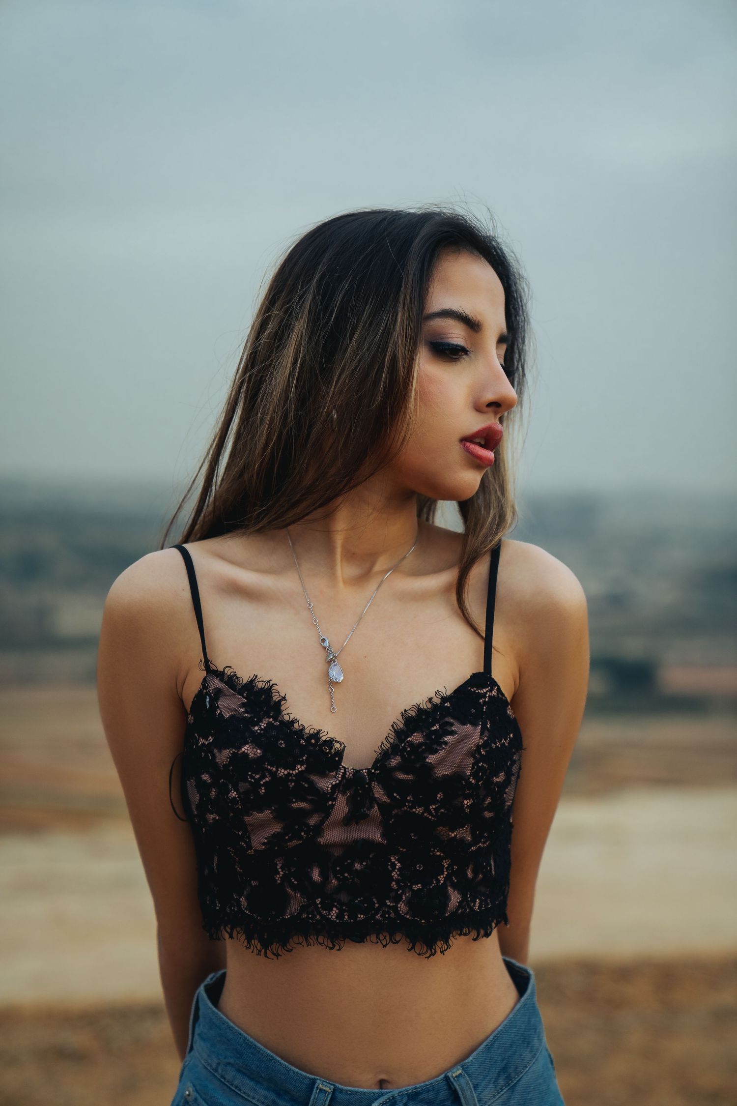 Fashion portrait in a desert landscape featuring black lace top and denim.