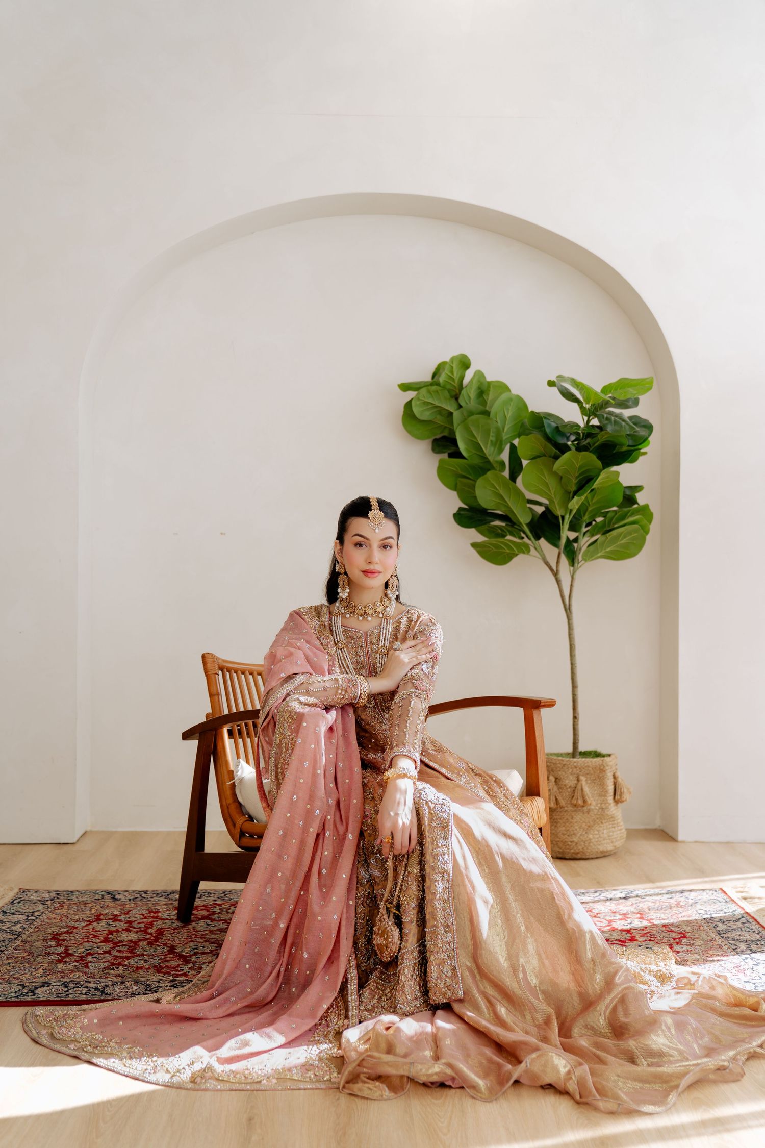 Elegant traditional South Asian bridal attire in blush pink with intricate embellishments.