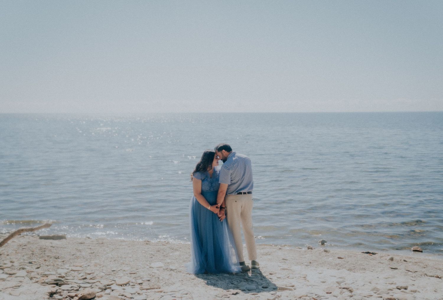 A couple shares tender moments on a rocky beach during a photo session.