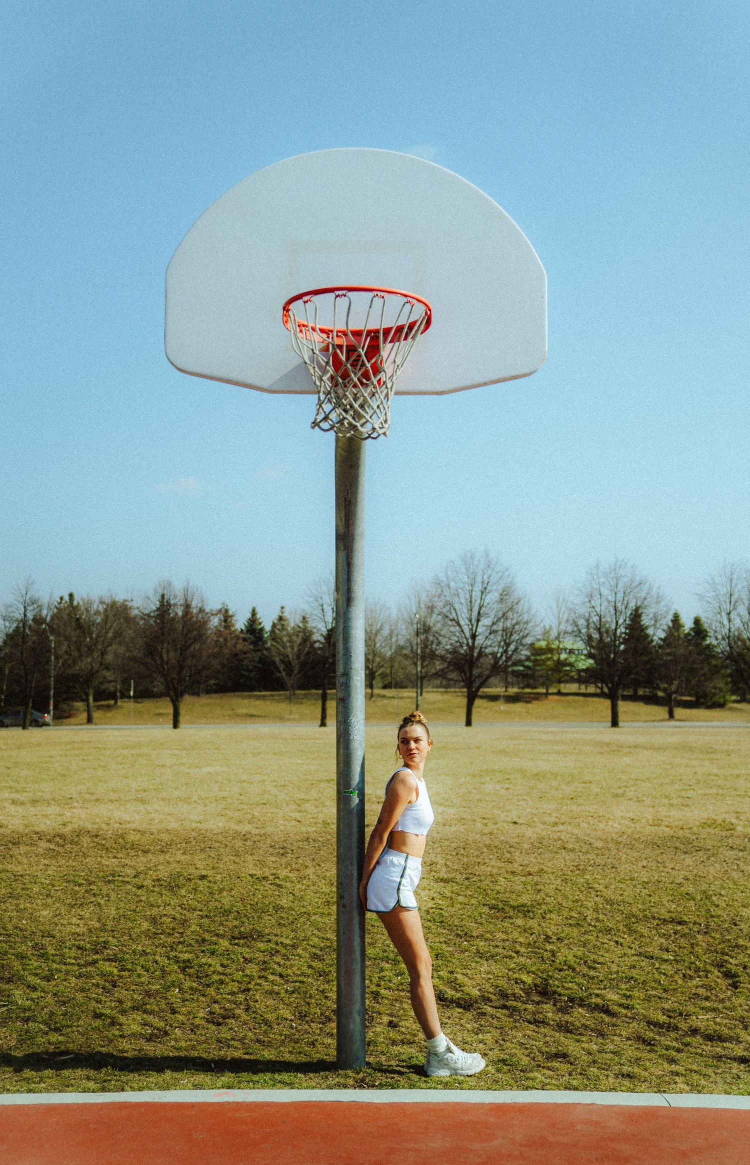 Basketball hoop stands tall against blue sky in outdoor court setting.