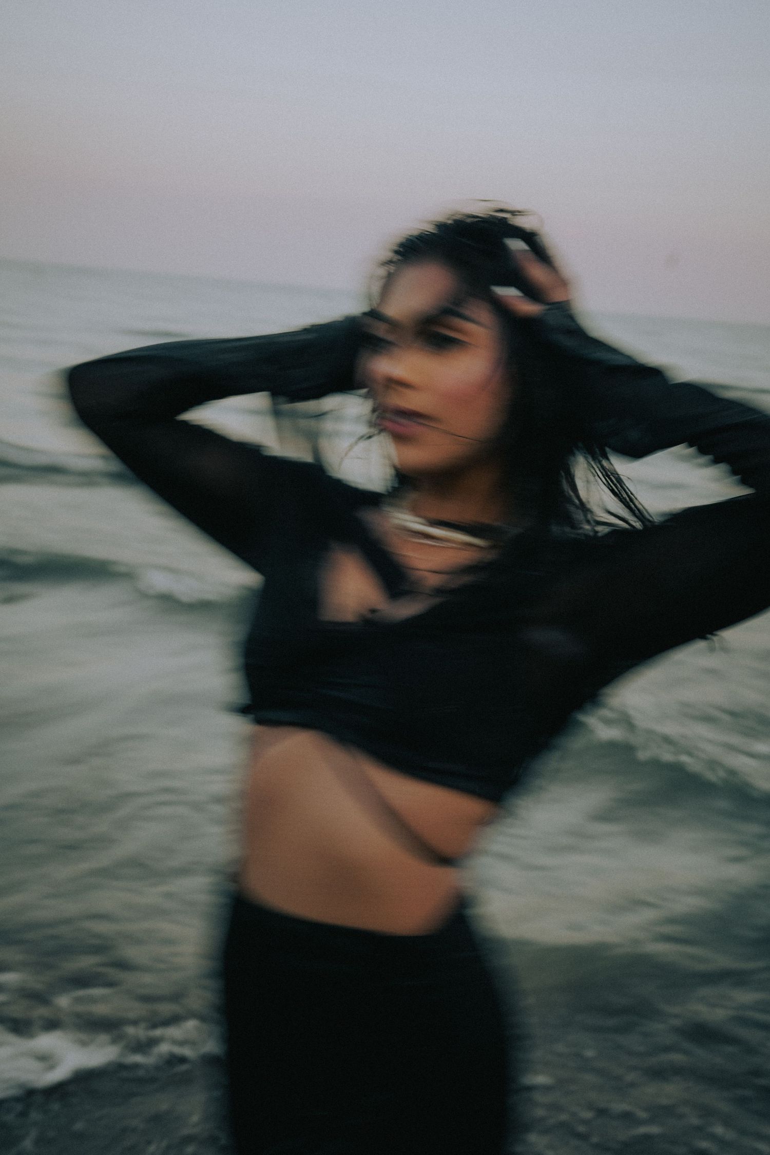 Artistic motion blur portraits at seaside with flowing dark clothing.