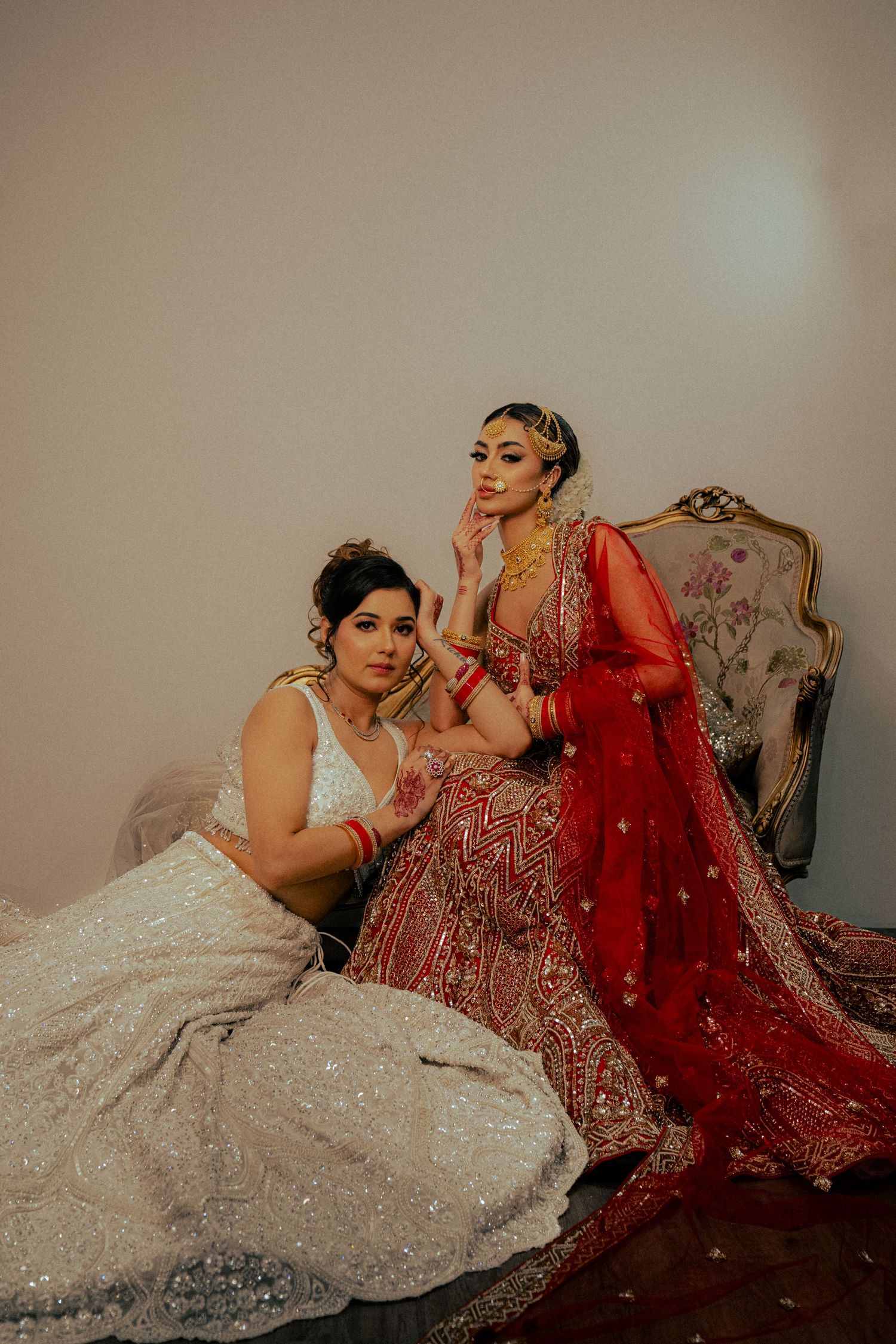 Two people in elegant formal attire lounging on decorative furniture.