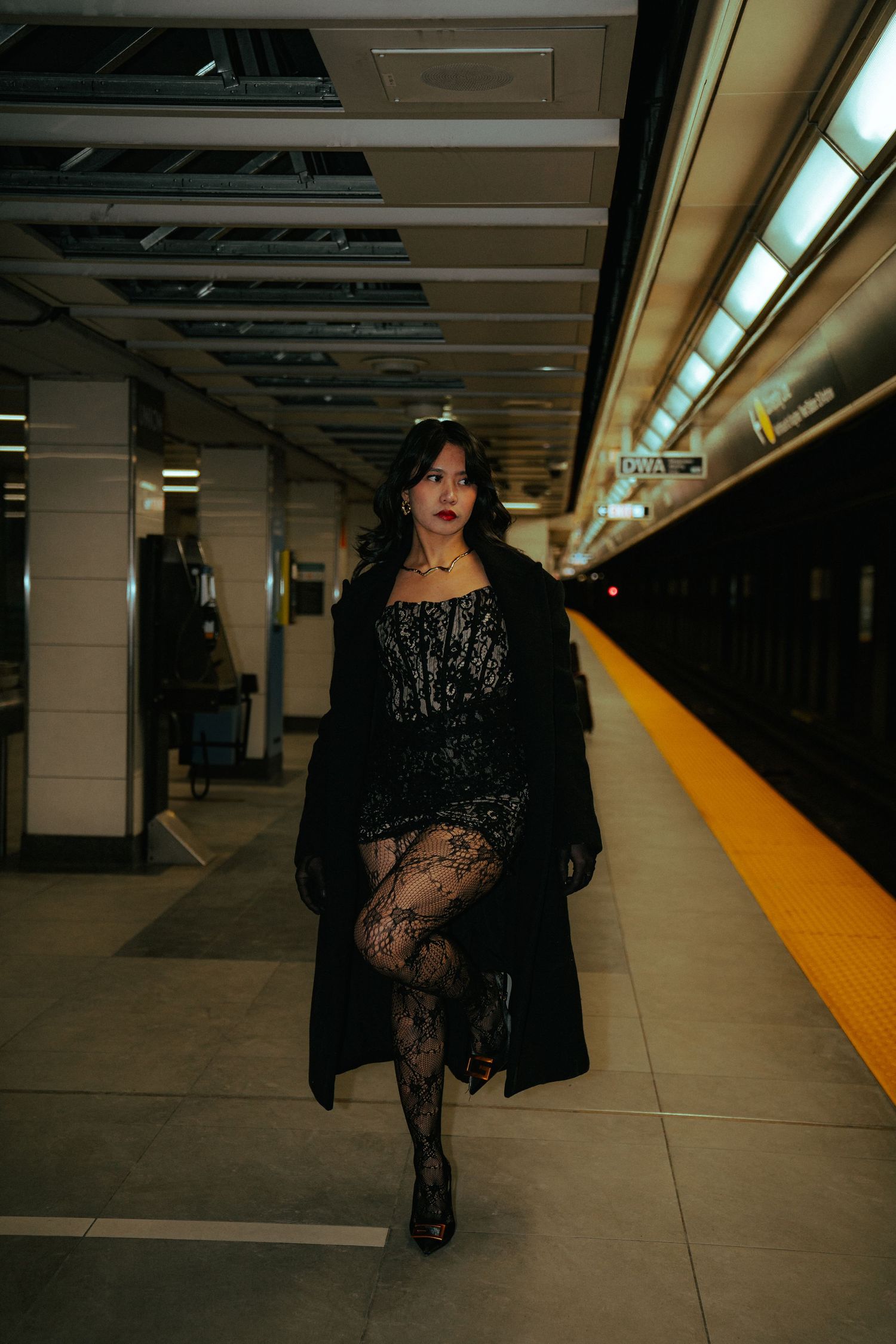 Dramatic fashion photoshoot in black lace dress at subway station platform.