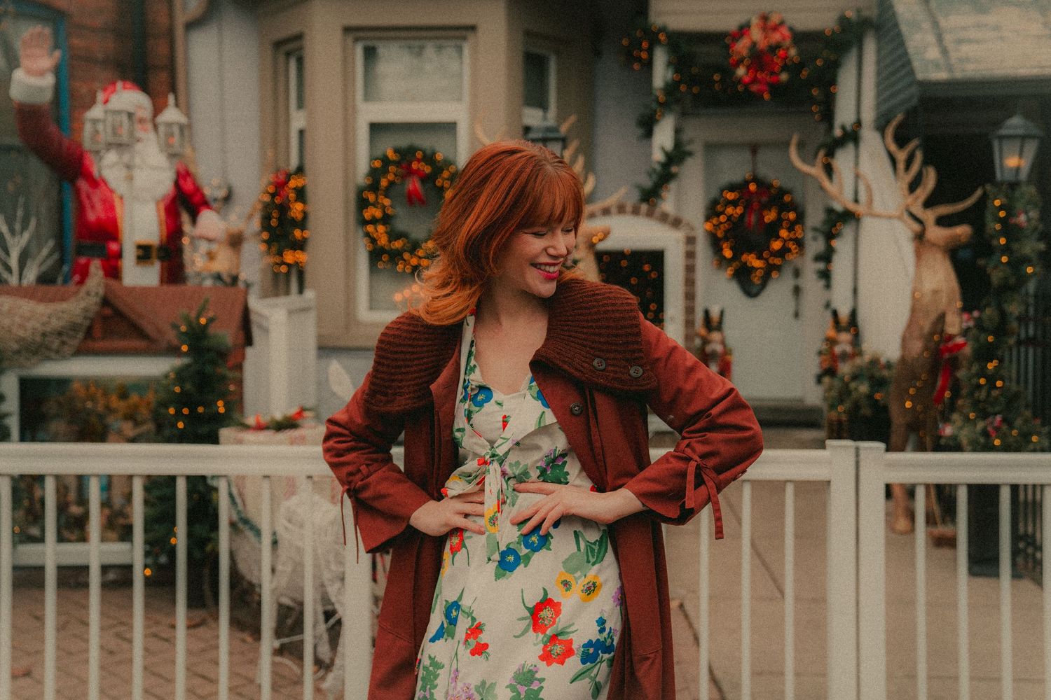 Autumn fashion photography with floral dress and burgundy cardigan on residential porch.