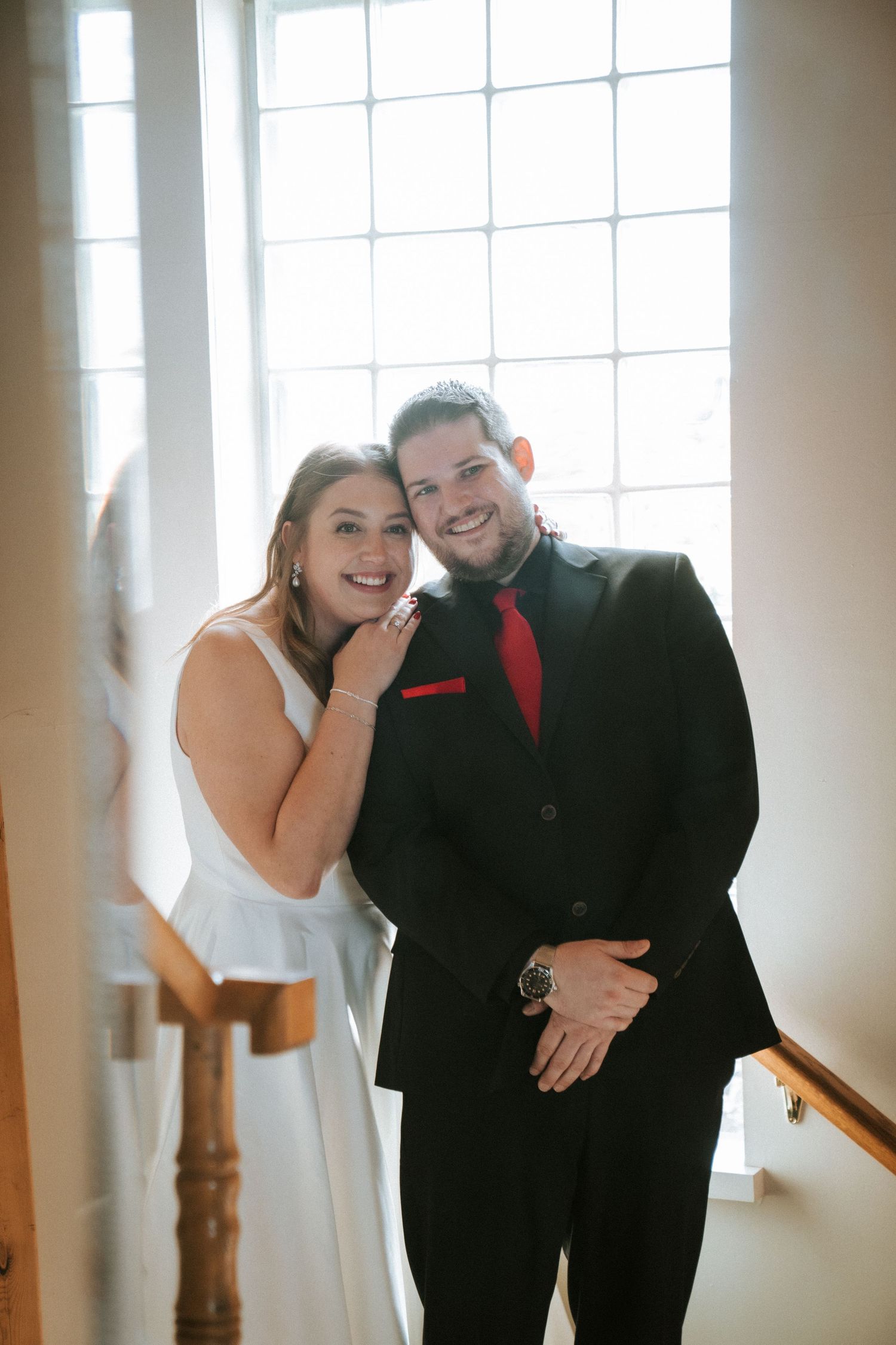 A playful black and white wedding photoshoot sequence showing a couple laughing together in a bright indoor setting.