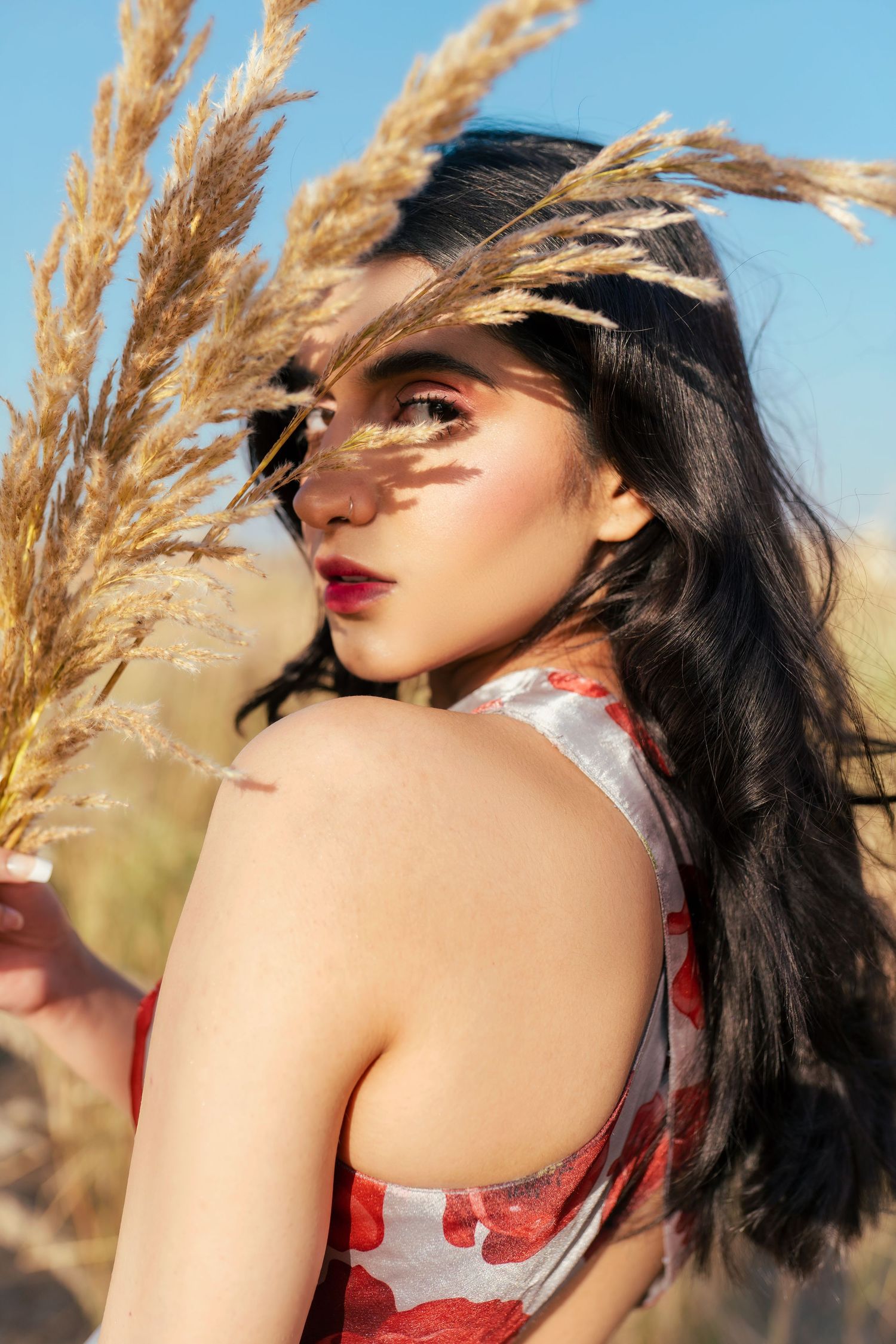 Dramatic portraits with wheat stalks against sunset sky.