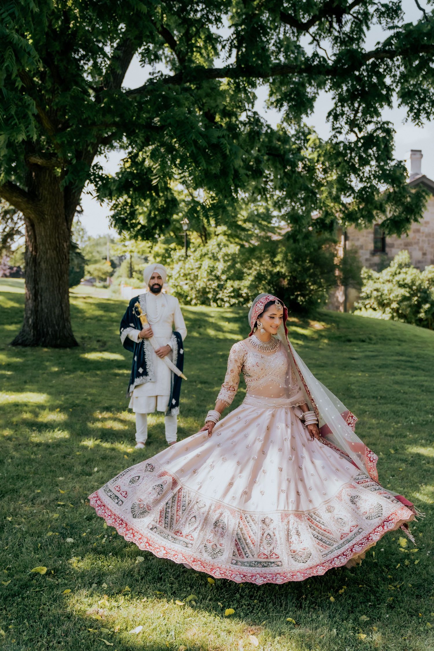 Traditional wedding attire with detailed embroidery twirling in a sunlit garden setting.