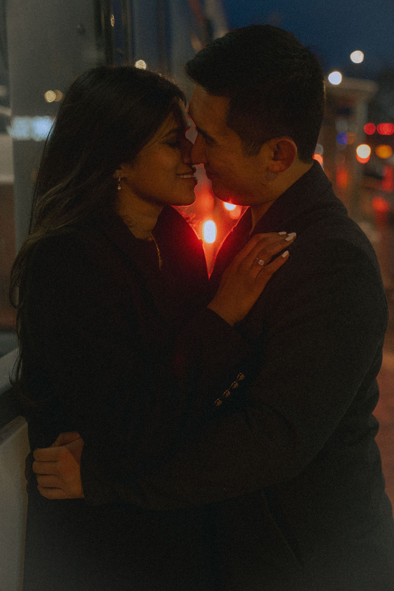 Romantic silhouette scene at night with city lights in background.
