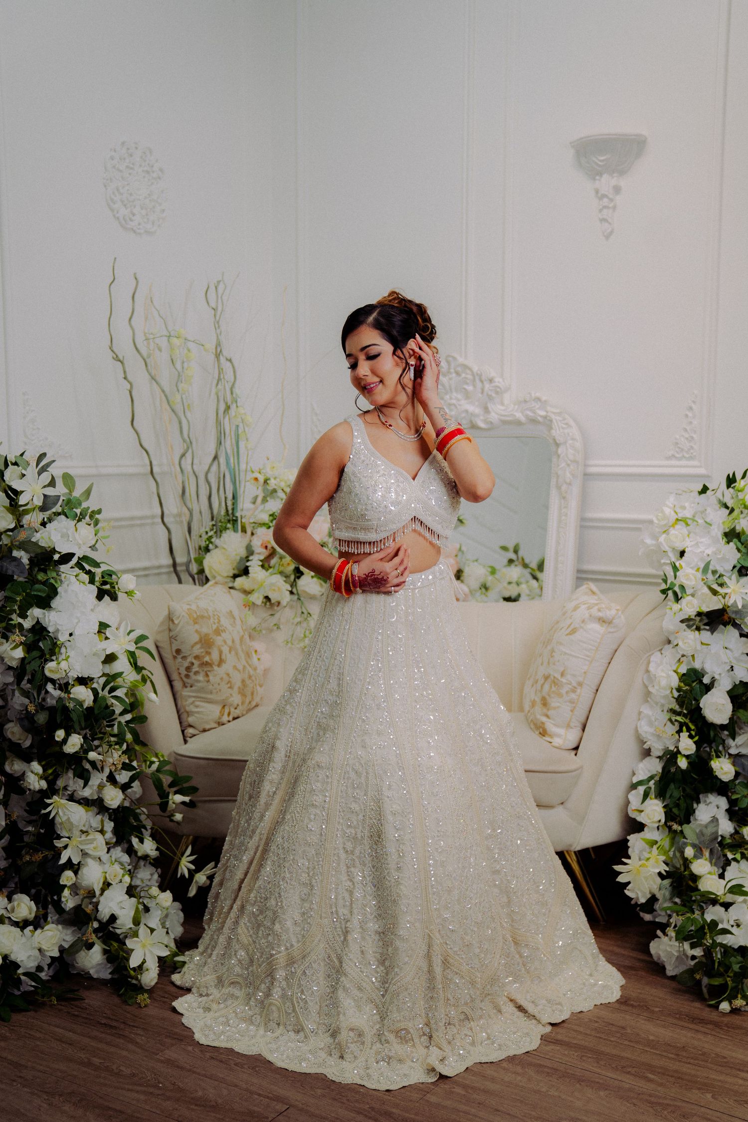 Elegant white wedding gown with floral decorations in a classic white room setting.