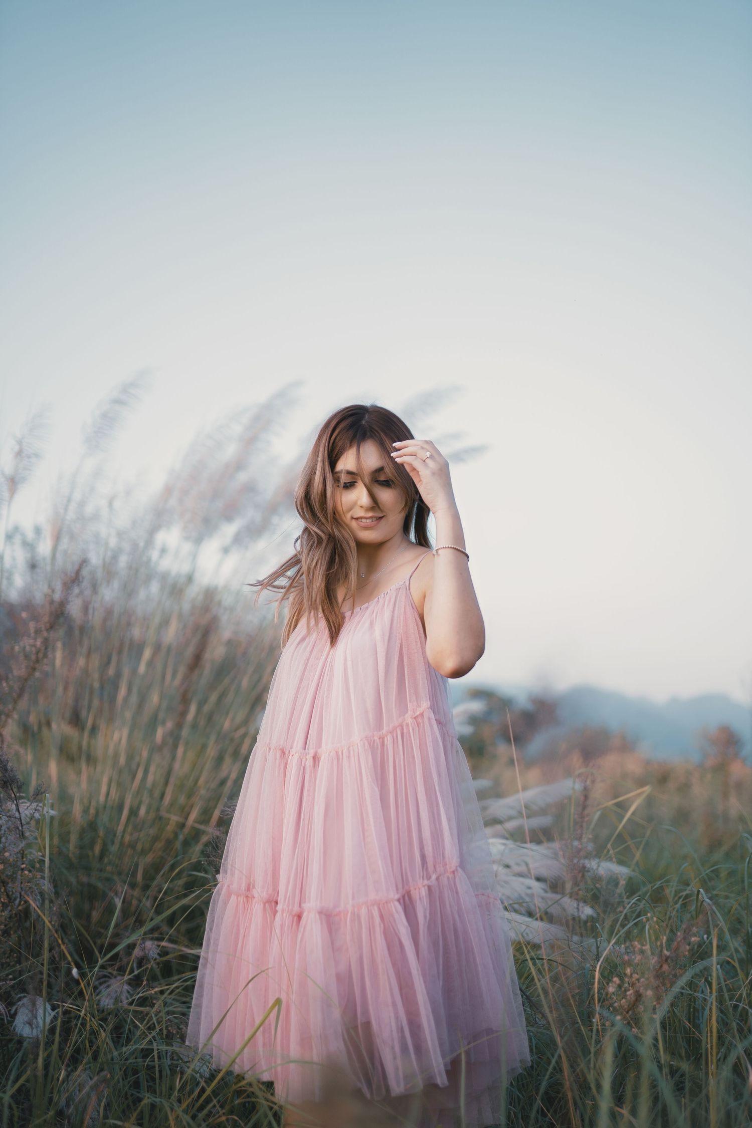 Ethereal outdoor photoshoot featuring flowing pink tulle dress in natural setting.