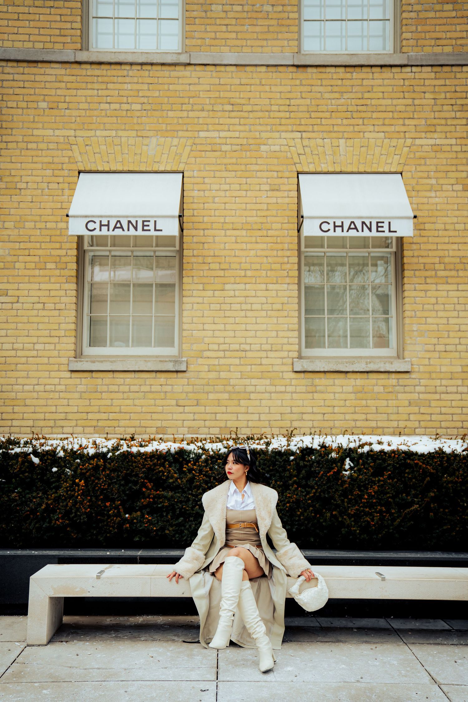 Minimalist fashion scene outside Chanel storefront with yellow brick wall.