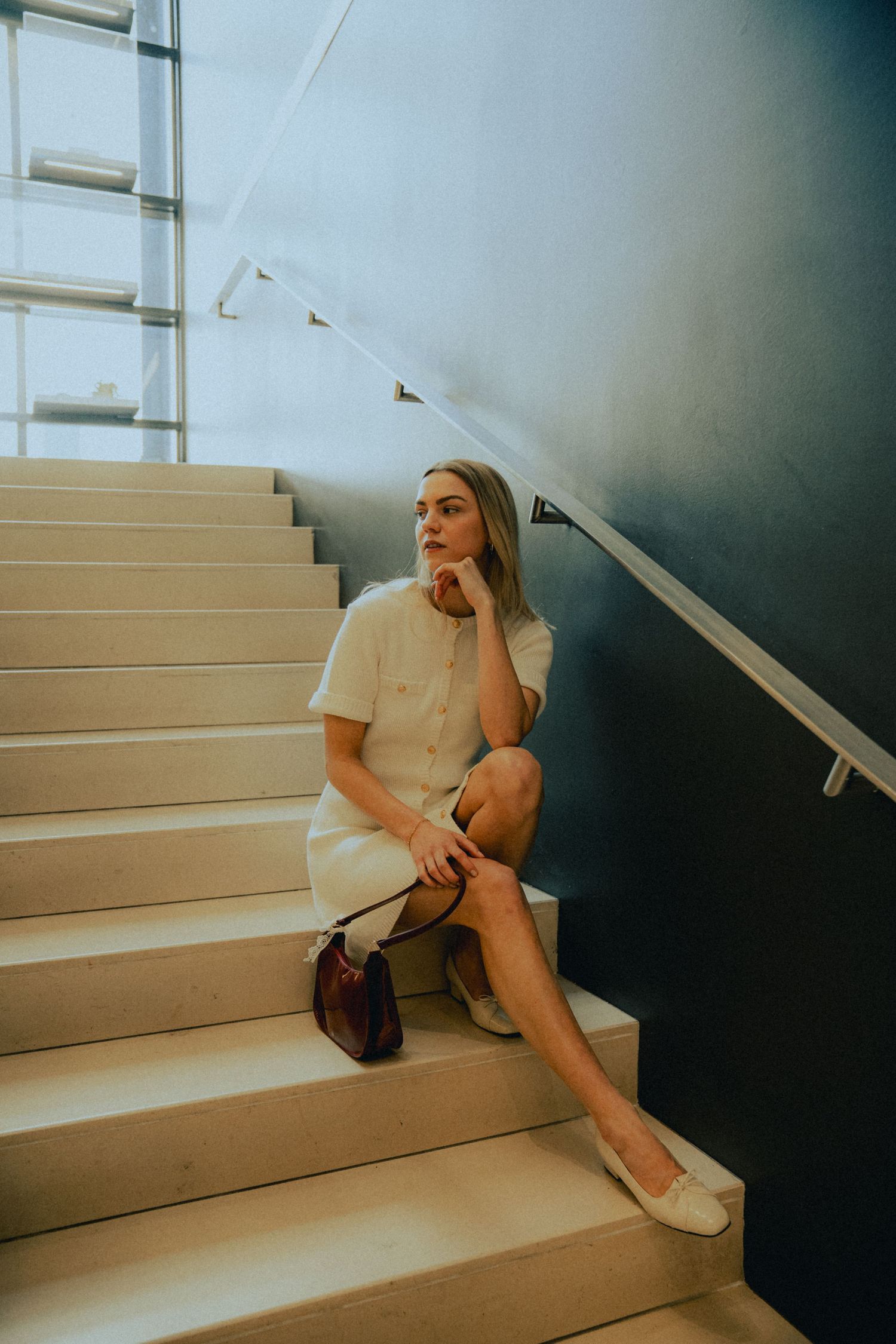 Moody fashion photography on modern concrete steps with dramatic lighting.