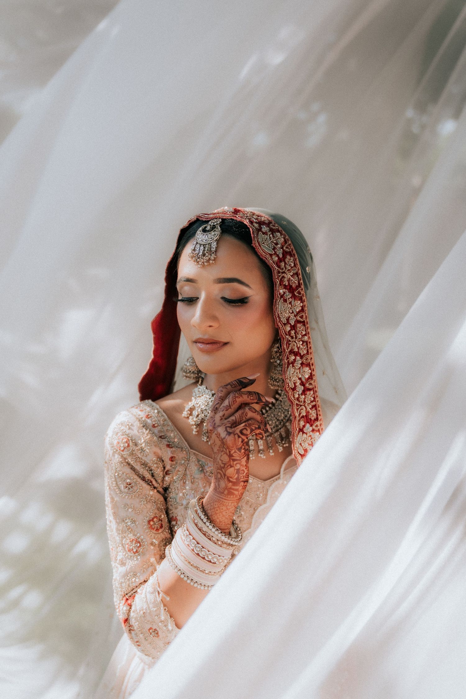 A traditional bridal portrait series featuring intricate henna designs and delicate white fabric.