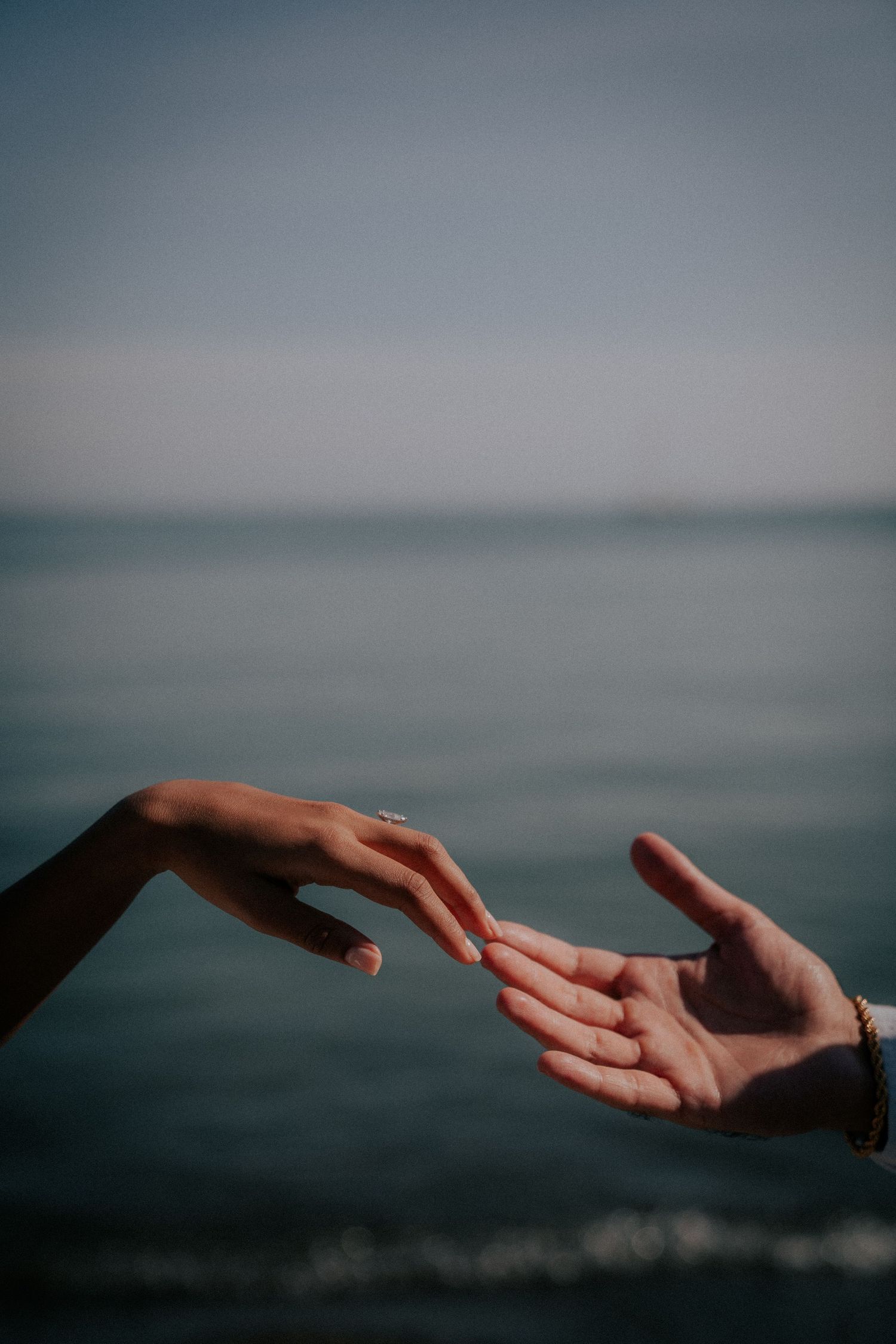 Artistic series of reaching hands against moody ocean backdrop creating emotional connection.
