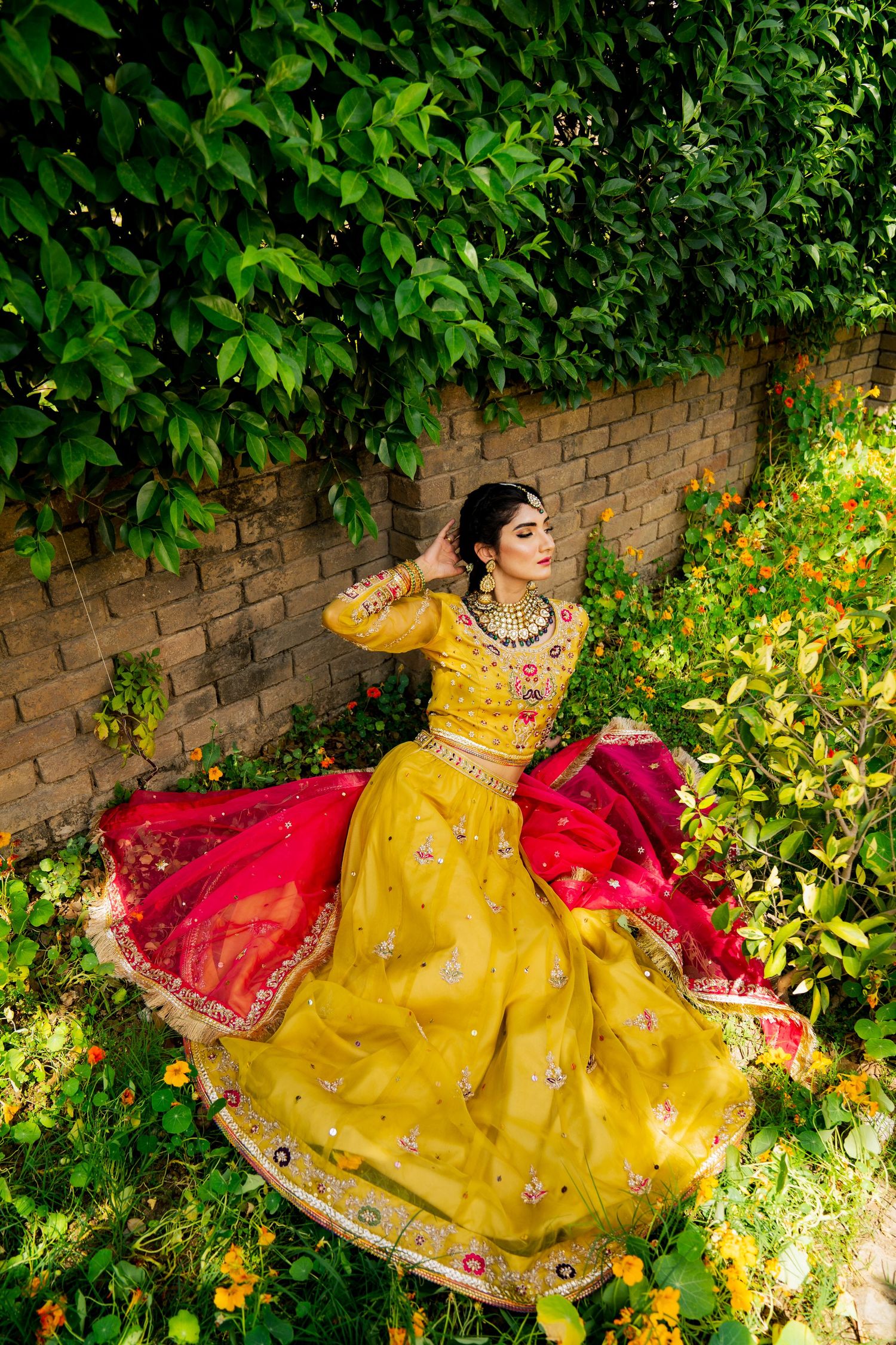 Person in vibrant yellow and red traditional dress twirling in a garden setting.
