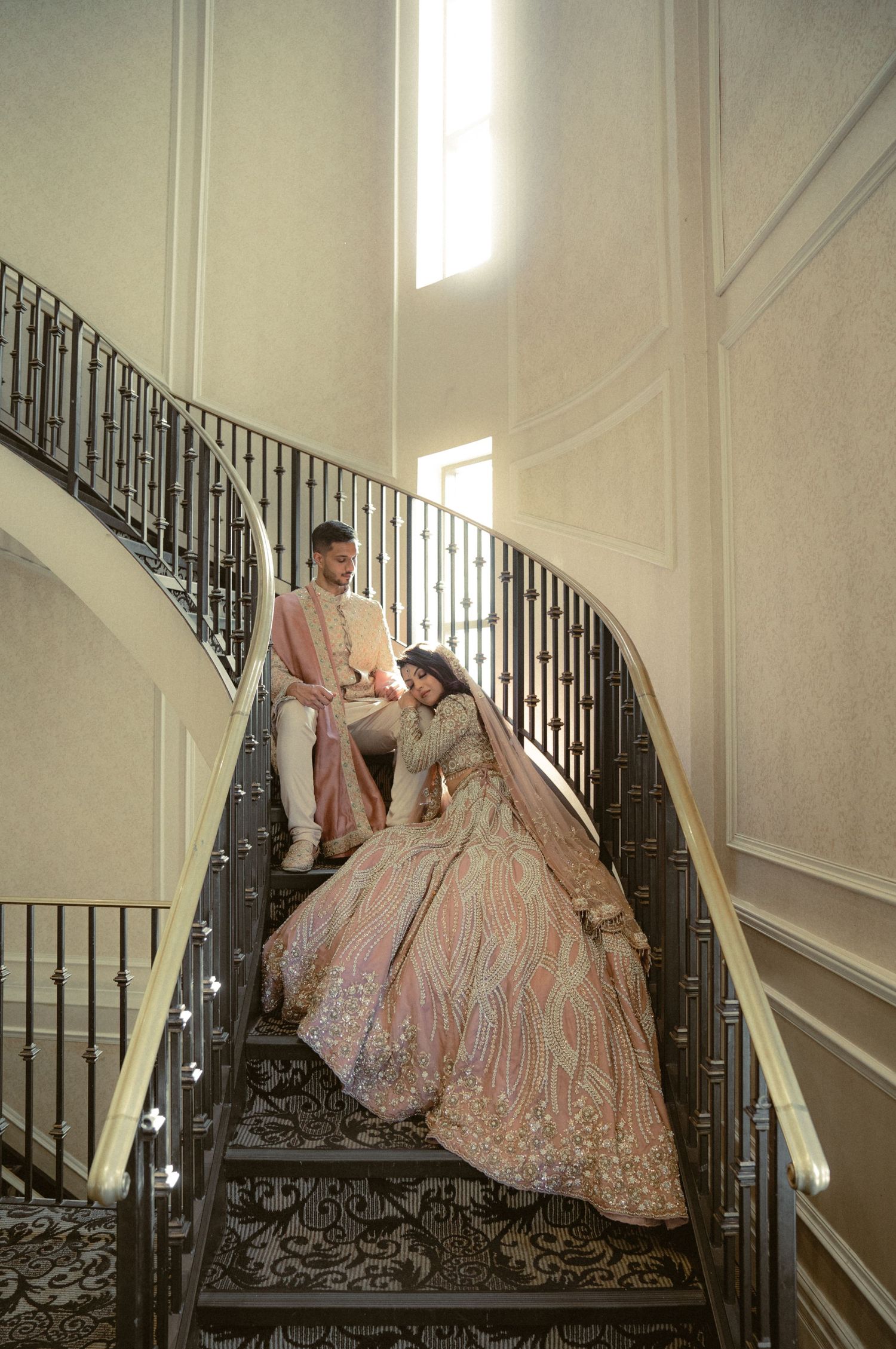 A romantic staircase photoshoot featuring elegant formal attire in soft lighting.