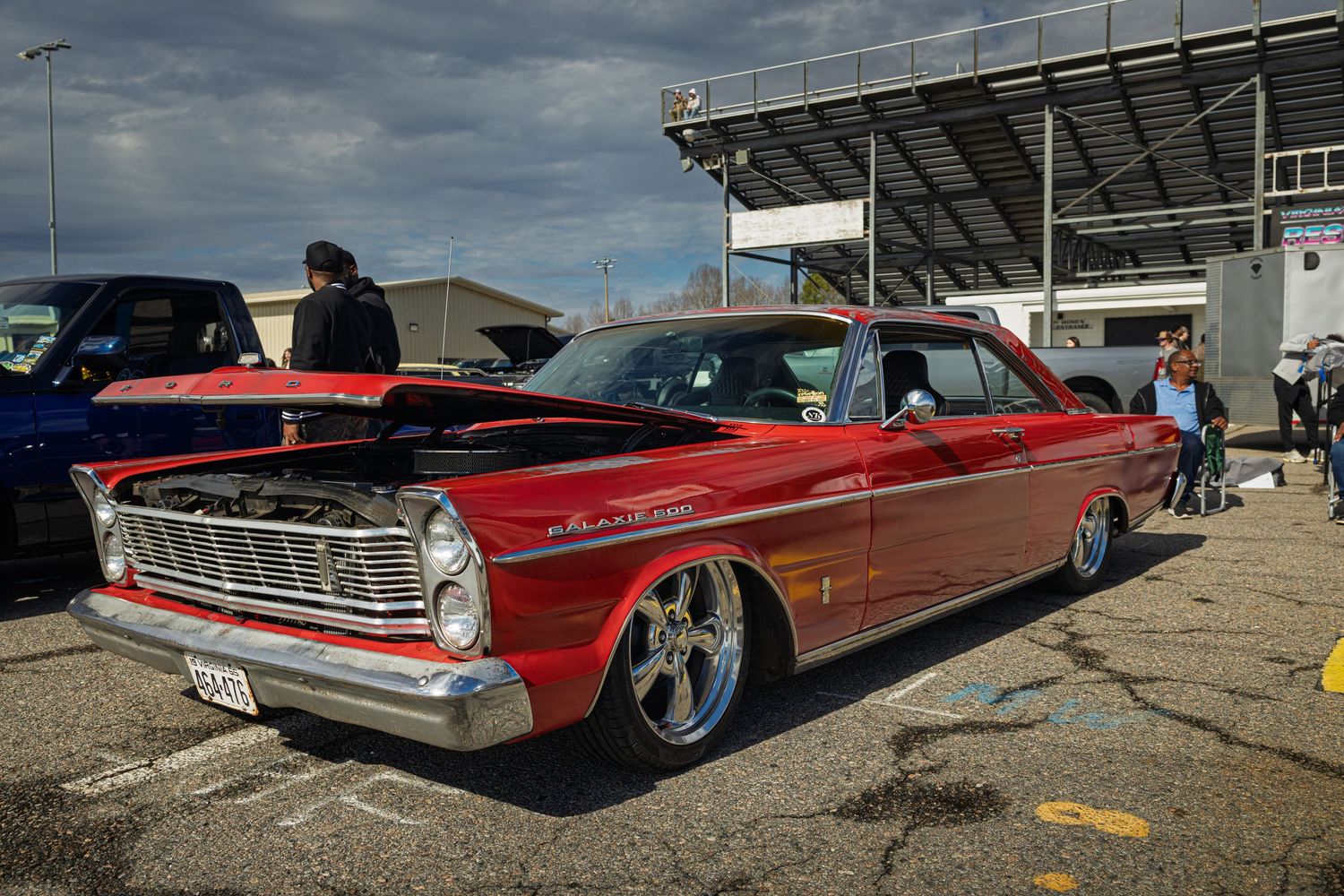 Ford Galaxie 500 classic lowrider cars in red and burgundy colors displayed at an outdoor auto show.