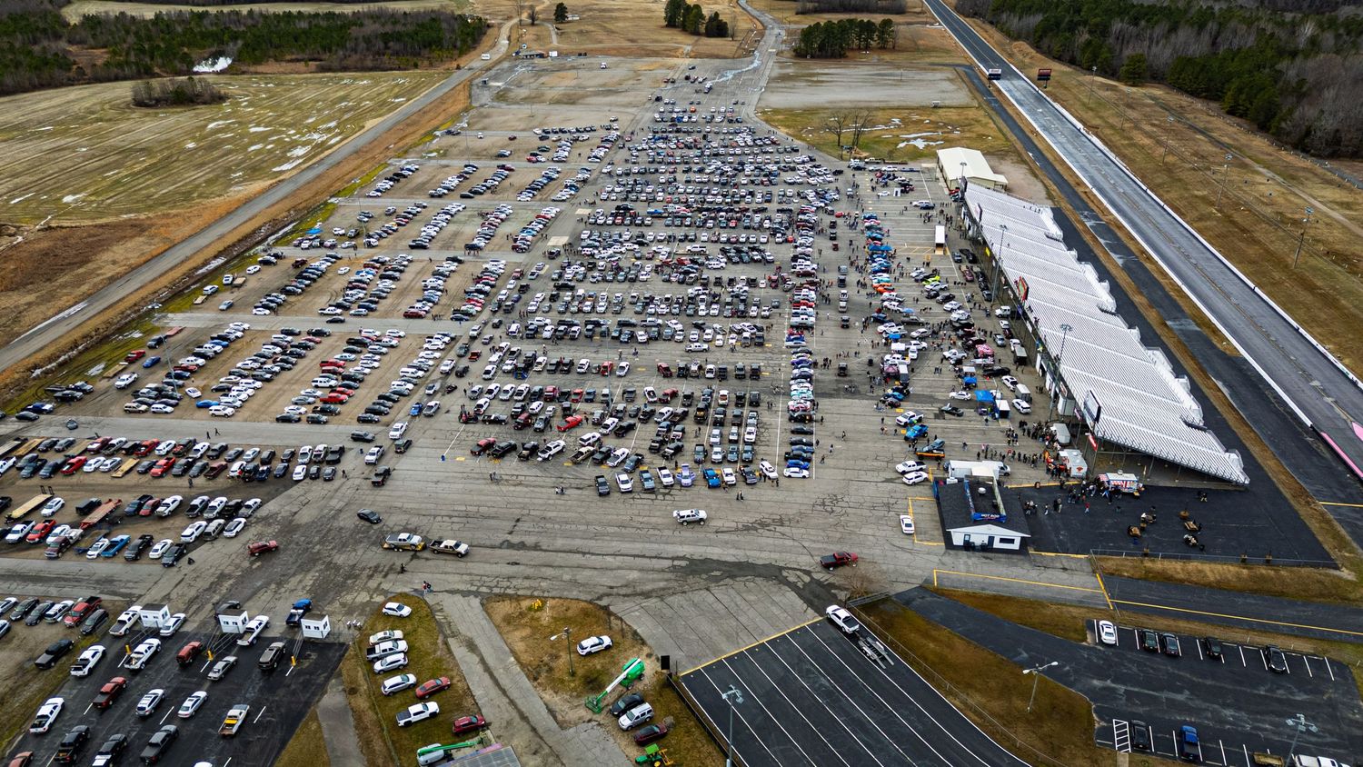 Aerial panoramic view of a large parking lot filled with vehicles near Virginia Motorsports Park drag strip.