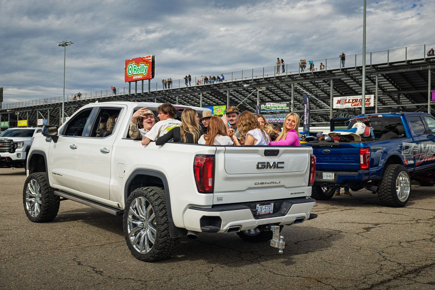 Lifted trucks with custom wheels and suspension modifications parked in a row at an outdoor event.